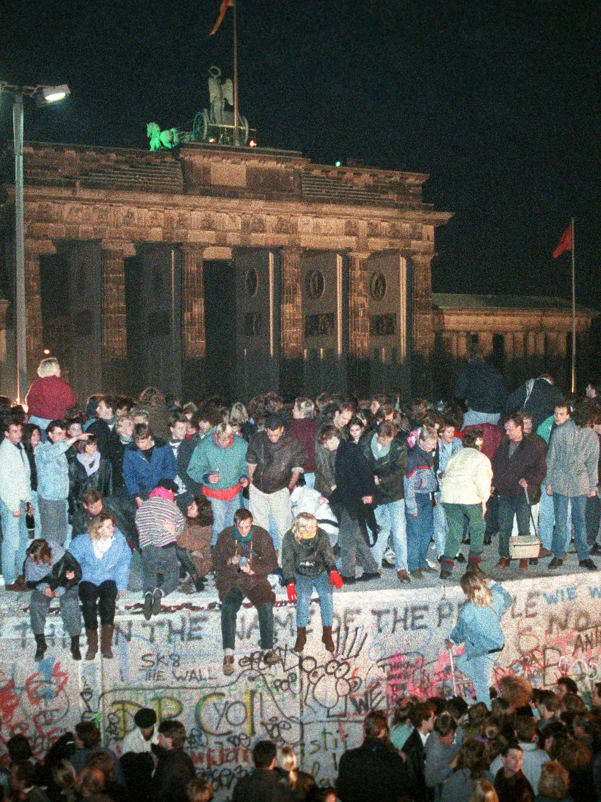 Menschen auf der Berliner Mauer vor dem Brandenburger Tor in der Nacht vom 9. auf den 10.11.1989. Vom 13.08.1961, dem Tag des Mauerbaus, bis zum Mauerfall am 09.11.1989 waren die Bundesrepublik Deutschland und die DDR durch den "Eisernen Vorhang" zwischen West und Ost getrennt. | Verwendung weltweit