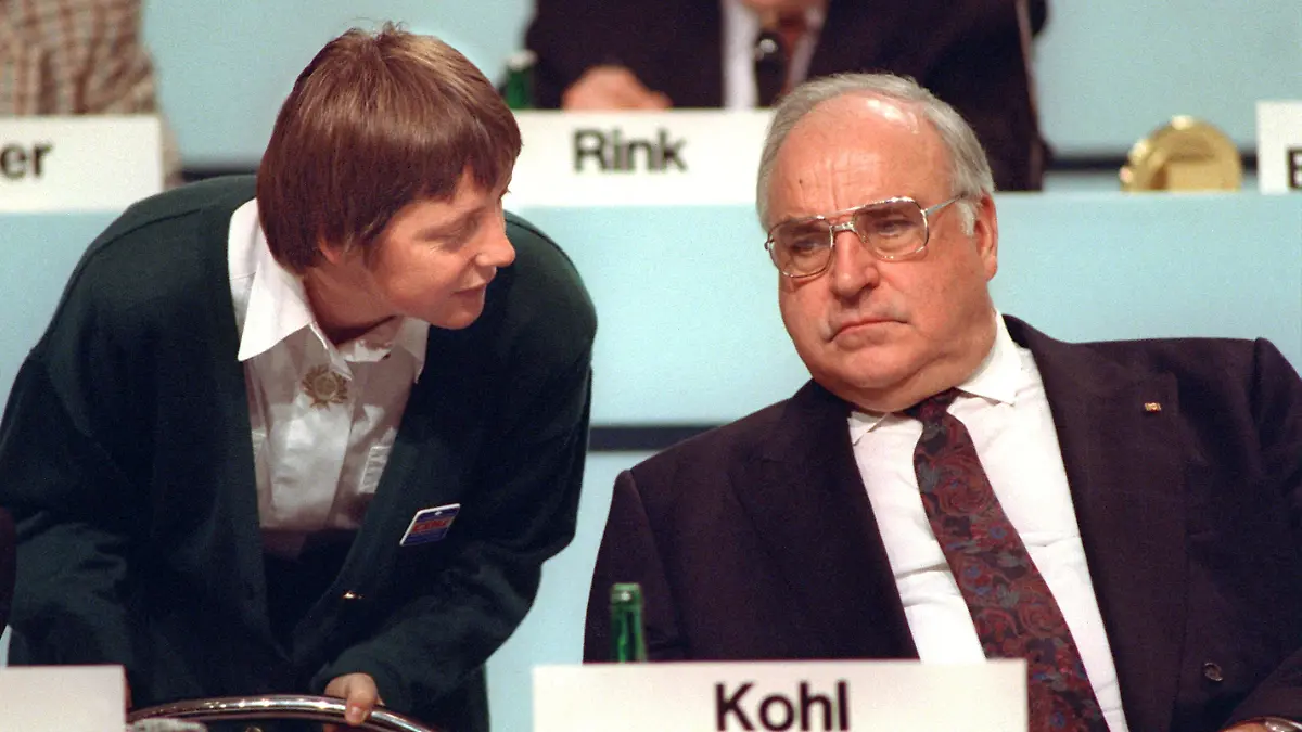 Bundesfrauenministerin Angela Merkel beugt sich am 16.12.1991 während des CDU-Parteitags in Dresden zu ihrem Mentor, Bundeskanzler Kohl, herab. Die Diplom-Physikerin, heute Generalsekretärin der Christdemokraten, wird auf dem CDU-Parteitag vom 9. bis 11.4.2000 in Essen für den Parteivorsitz kandidieren. Die 45-Jährige wäre die erste Frau an der Spitze der Unionspartei - eine Blitzkarriere: Während der Wende engagierte sie sich im "Demokratischen Aufbruch". Nach den ersten freien Volkskammerwahlen war sie stellvertretende Regierungssprecherin der DDR und trat im August 1990 in die Union ein. 1991 holte Kanzler Kohl sie als Ministerin für Frauen und Jugend in sein Kabinett, 1993 wurde sie CDU-Landesvorsitzende in Mecklenburg- Vorpommern, 1994 Bundesumweltministerin. Nach der Niederlage der Christdemokraten bei den Bundestagswahlen 1998 wurde sie zur Generalsekretärin ihrer Partei gewählt.