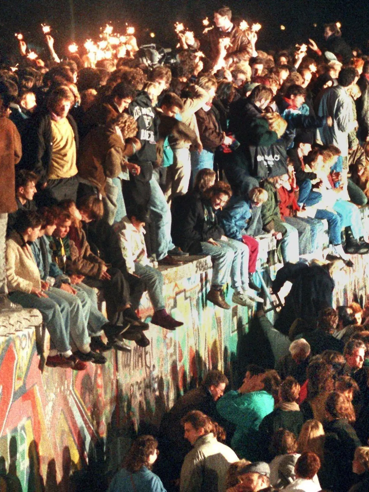 ARCHIV - 11.11.1989, Berlin: Jubelnde Menschen sitzen mit Wunderkerzen auf der Berliner Mauer am 11.11.1989. (zu "Themenpaket 30 Jahre Mauerfall am 9. November 1989") Foto: dpa +++ dpa-Bildfunk +++