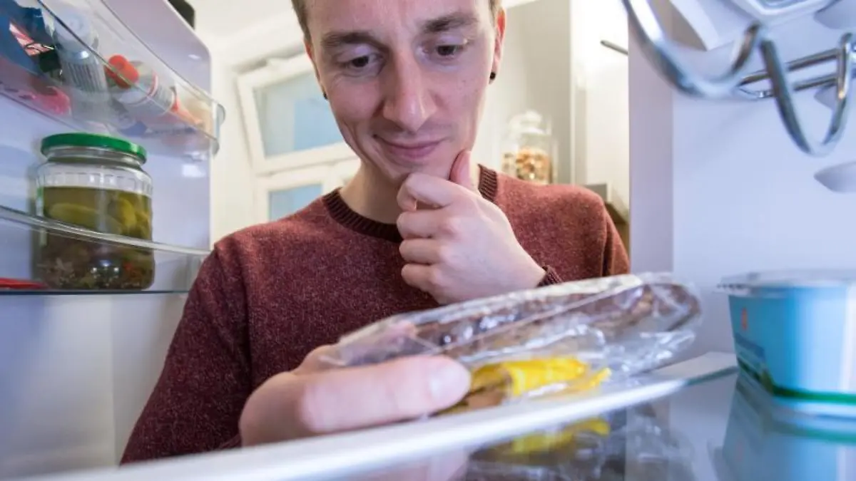 Mann guckt in Kühlschrank