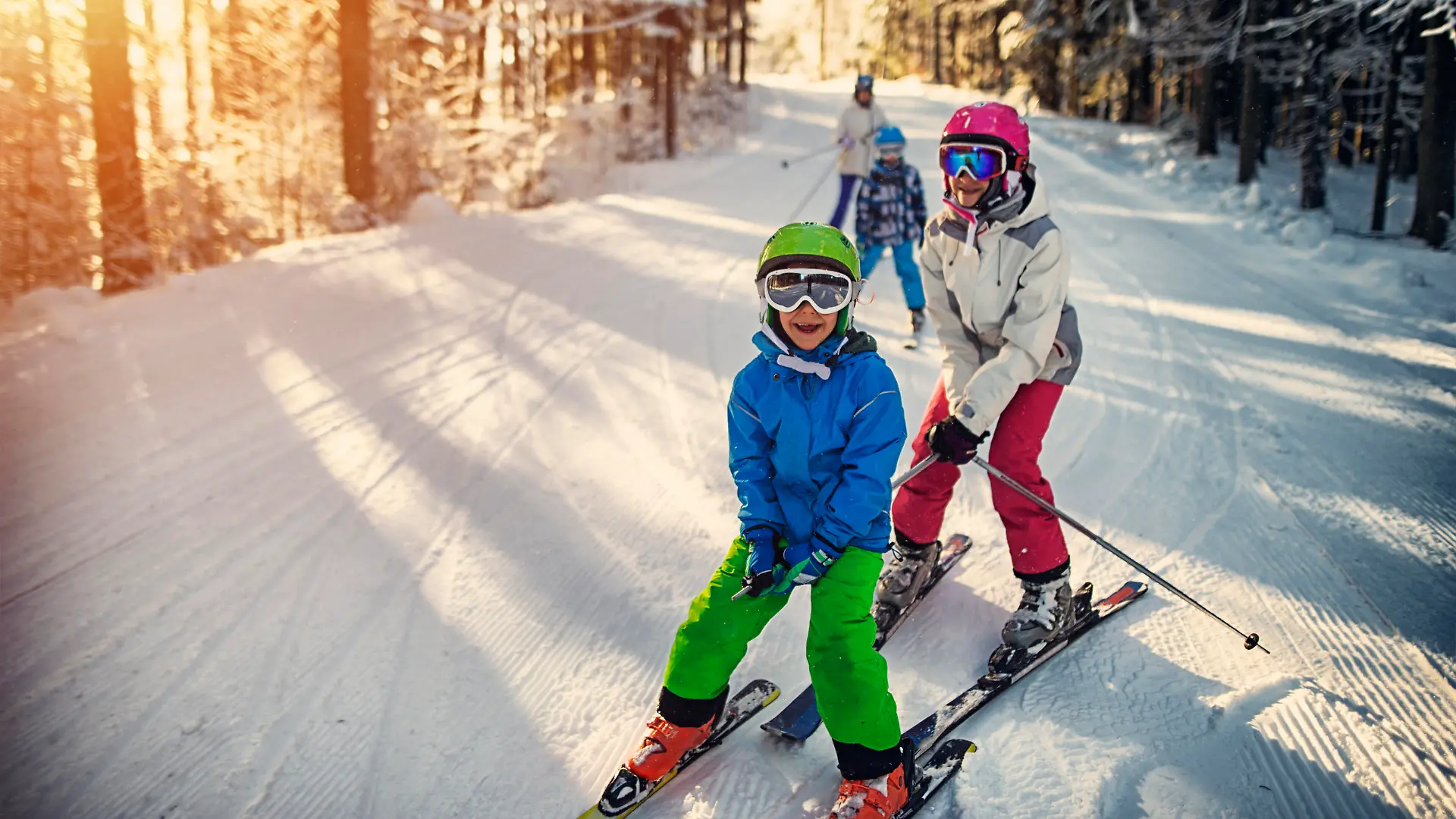 Mother with kids are skiing together down the ski slope. Everybody is laughing happily. 


