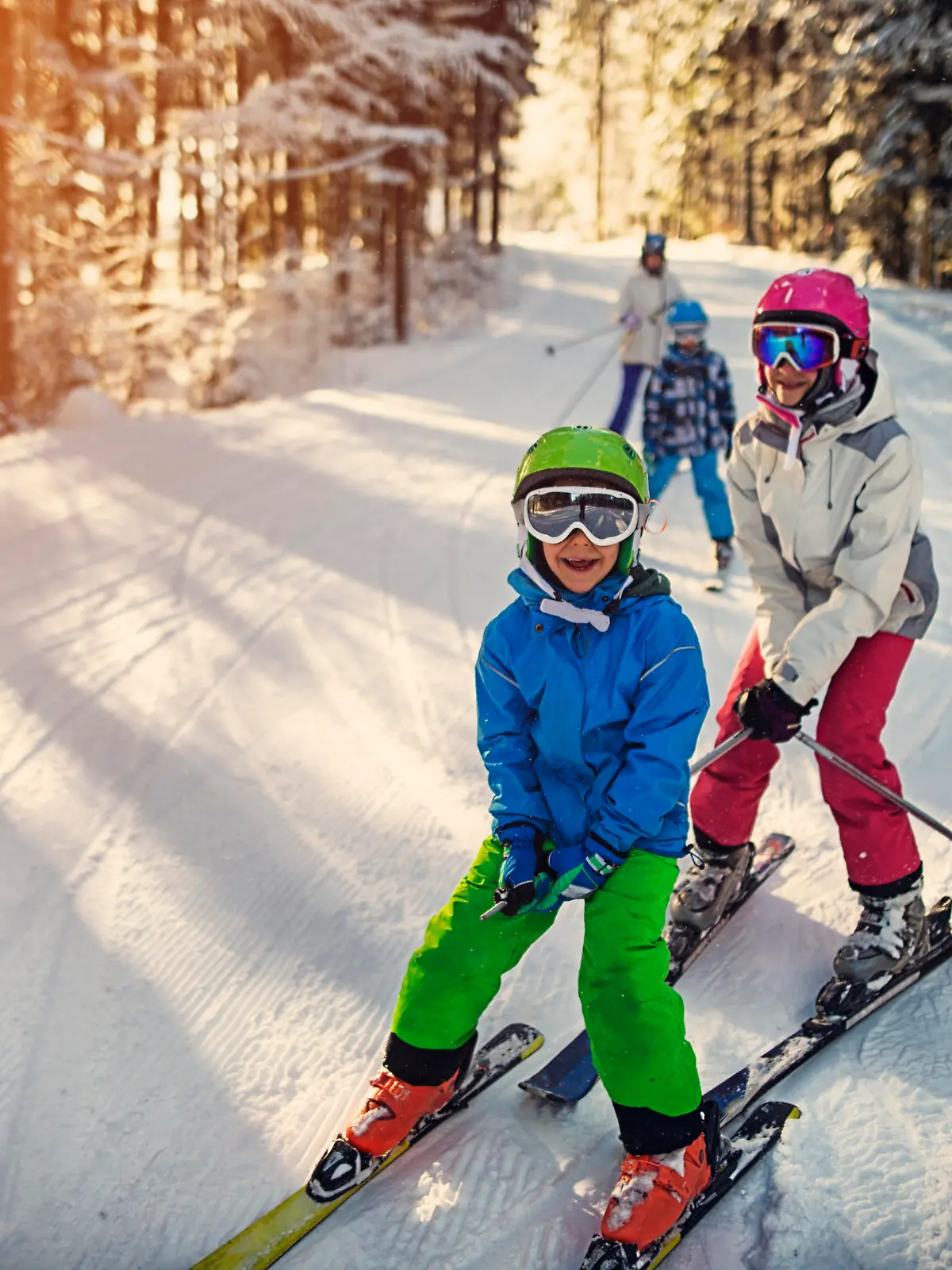 Mother with kids are skiing together down the ski slope. Everybody is laughing happily. 

