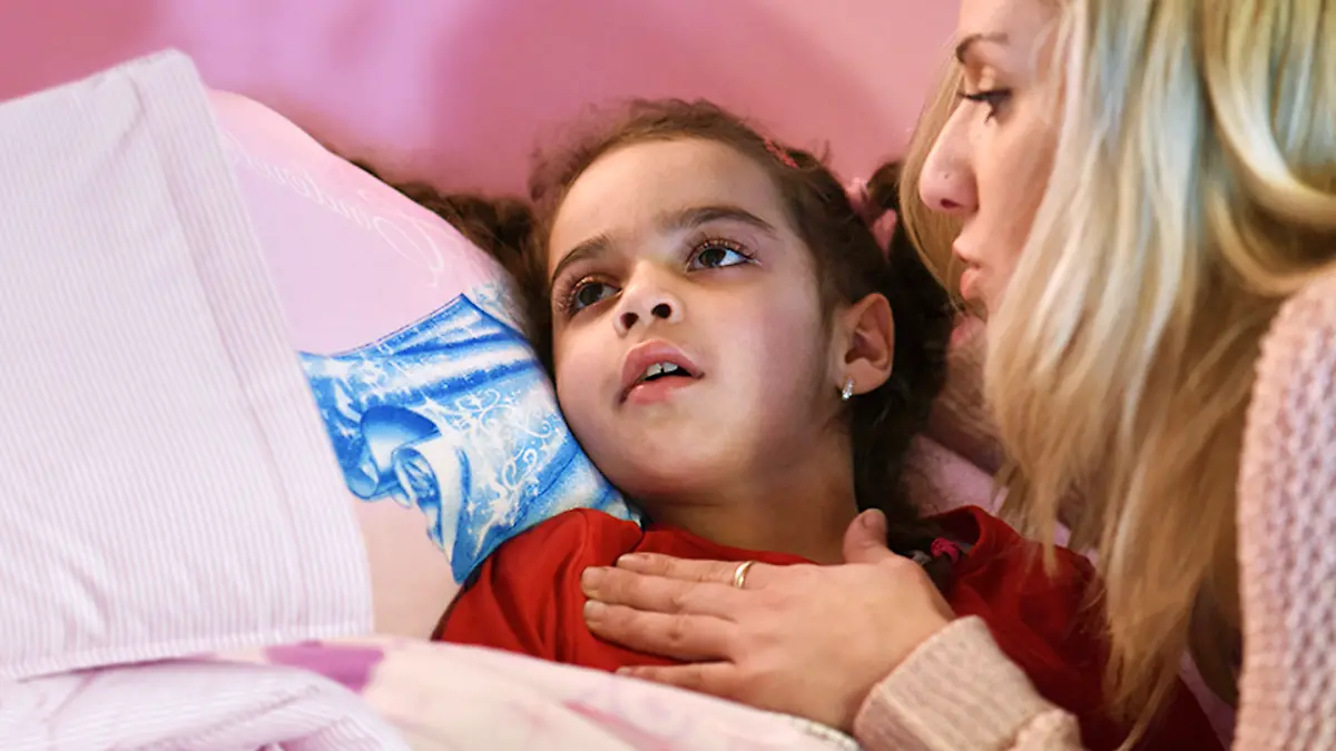 Mama Mirella Kunzmann (l) spricht am 30.10.2014 in Bad Hersfeld (Hessen) zu ihrer kranken Tochter Aliana. Sie leidet an der chronischen Maserngehirnentzündung SSPE, die Spätfolge einer Maserninfektion, die immer tödlich verläuft.