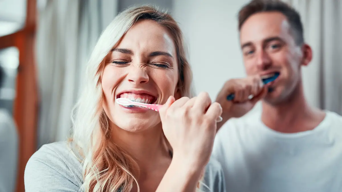 Portrait of a young couple brushing their teeth together in the bathroom at home