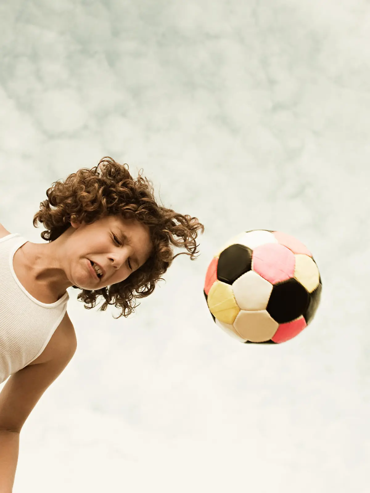 Kind köpft Ball beim Fußballspielen