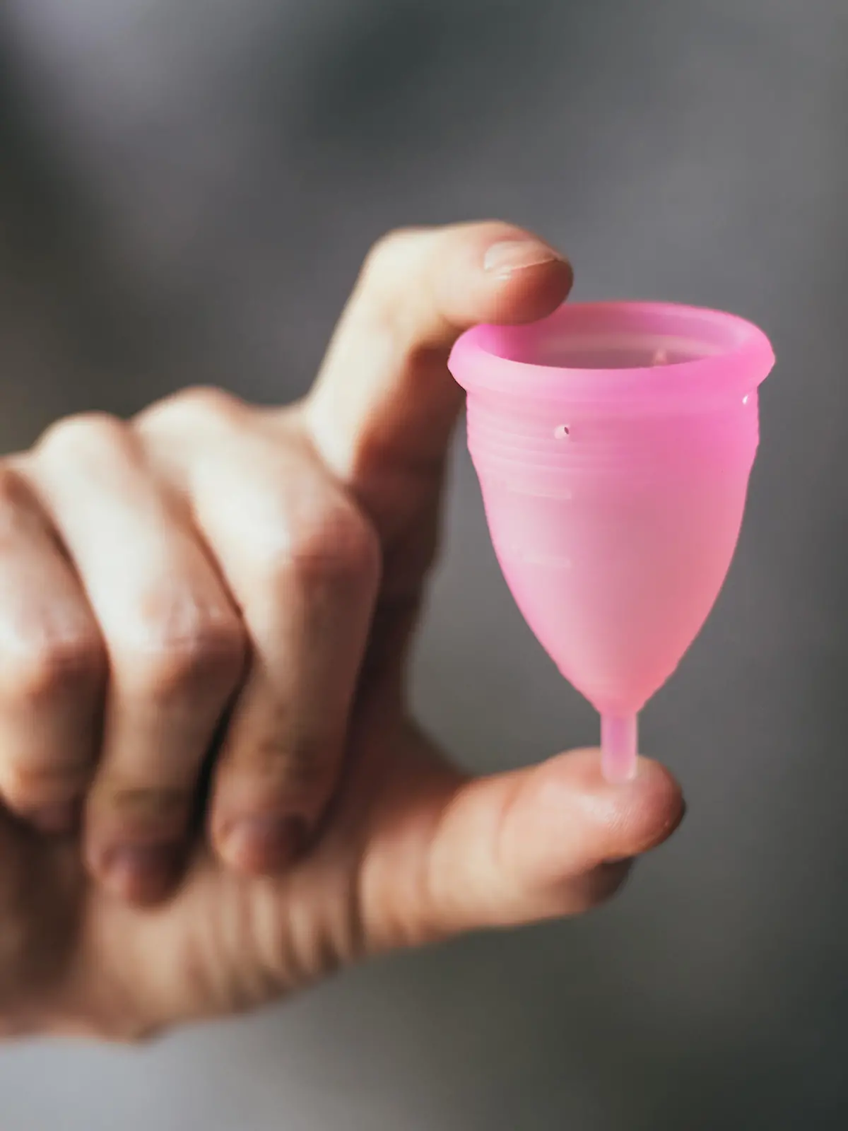Young woman hand holding menstrual cup. Selective focus and shallow DOF