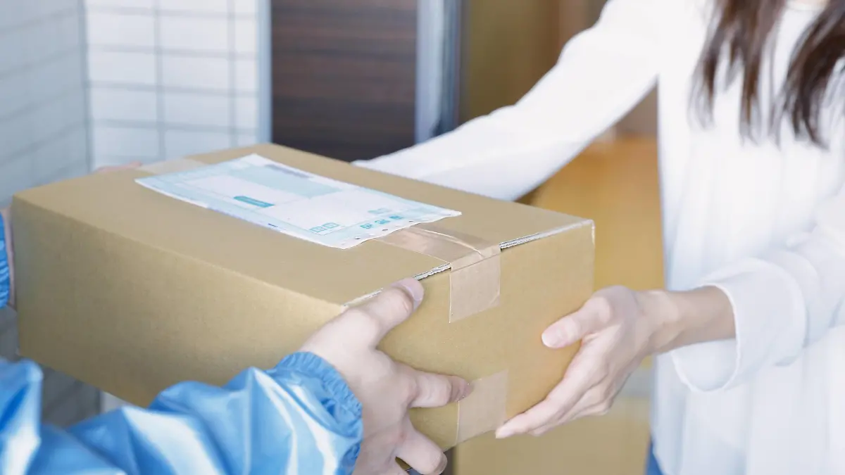  Young Japanese woman getting package from delivery man PUBLICATIONxINxGERxSUIxAUTxHUNxONLY jjig004118
