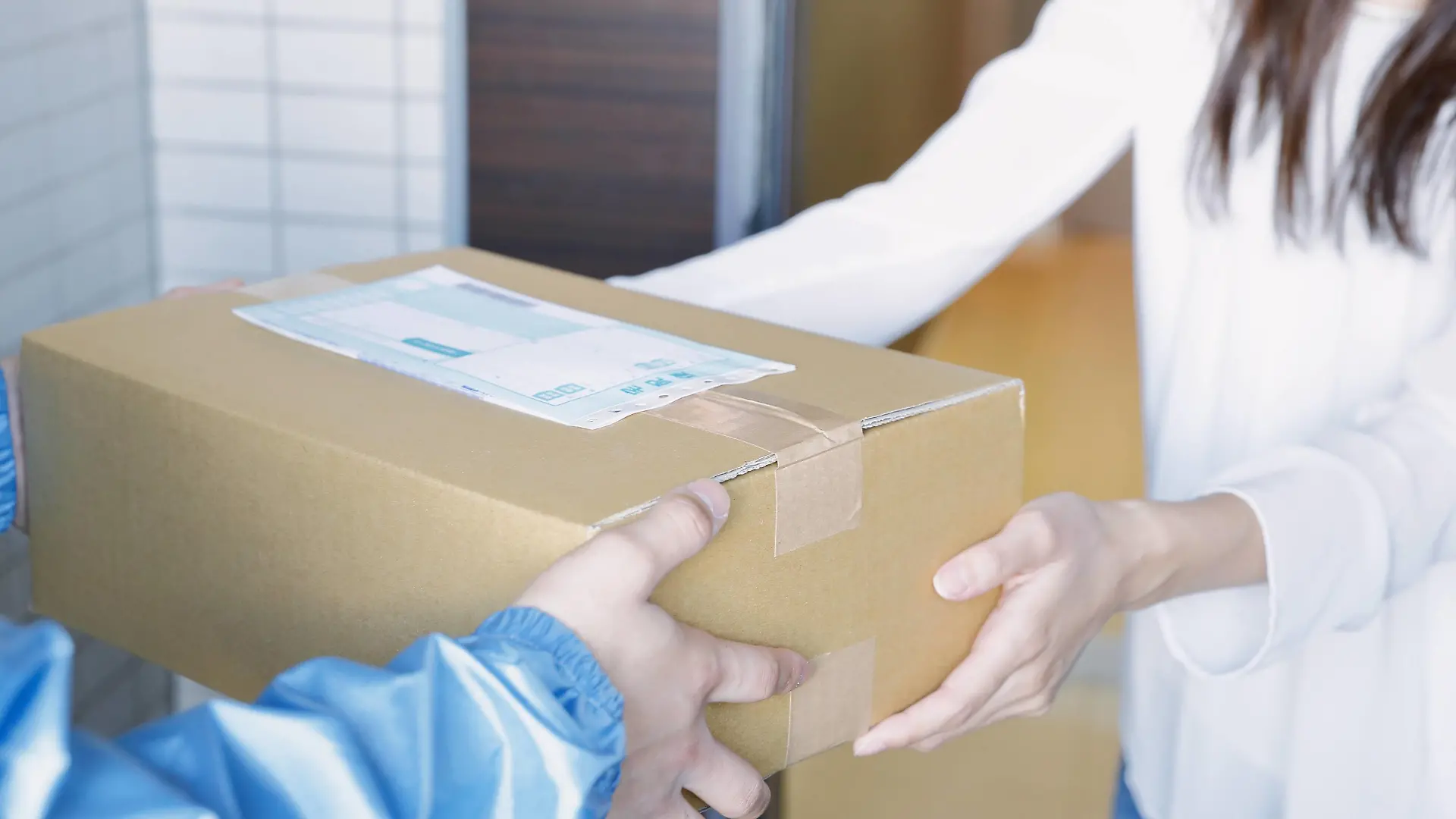  Young Japanese woman getting package from delivery man PUBLICATIONxINxGERxSUIxAUTxHUNxONLY jjig004118
