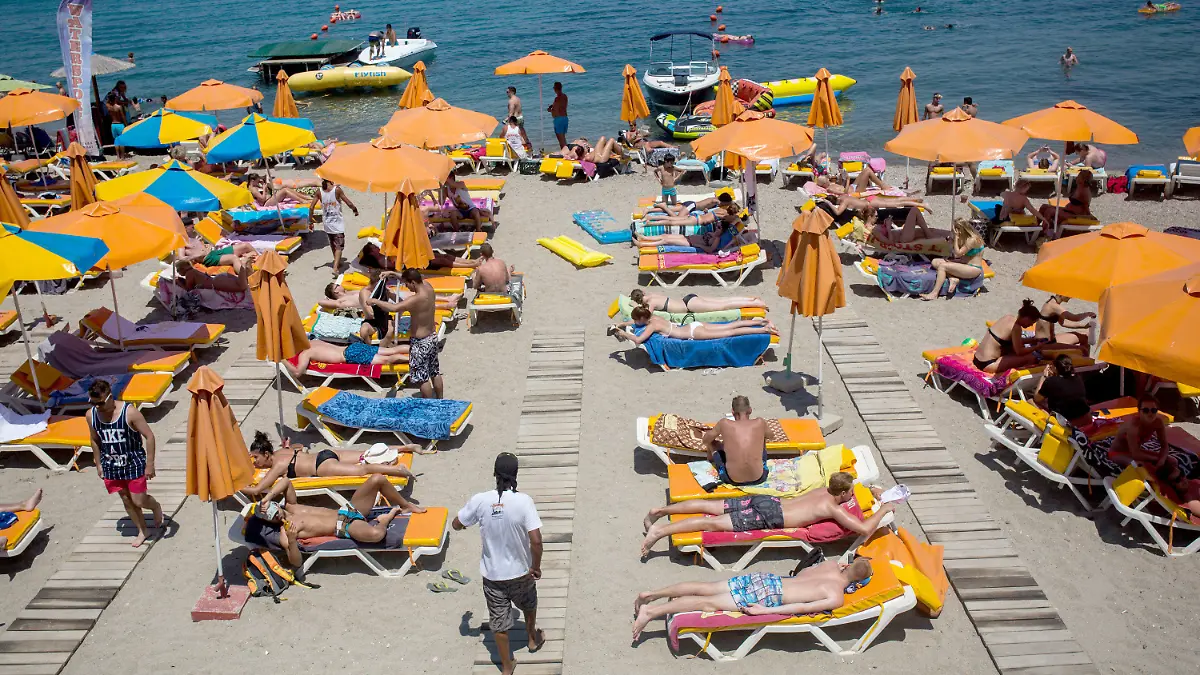 ARCHIV - 10.07.2015, Griechenland, Kos: Touristen genießen die Sonne an einem Strand nahe der Stadt Kos auf der gleichnamigen griechischen Insel. Die Chancen auf Urlaub am Mittelmeer steigen: Bundesaußenminister Maas verständigte sich am 18.05.2020 mit seinen Kollegen aus zehn der beliebtesten Urlaubsländer der Deutschen darauf, auf eine Öffnung der Grenzen für Touristen bis zum Sommerbeginn hinzuarbeiten. (Zu dpa "Urlaub am Mittelmeer rückt näher - Maas will Reisewarnung aufheben") Foto: Santi Palacios/dpa +++ dpa-Bildfunk +++
