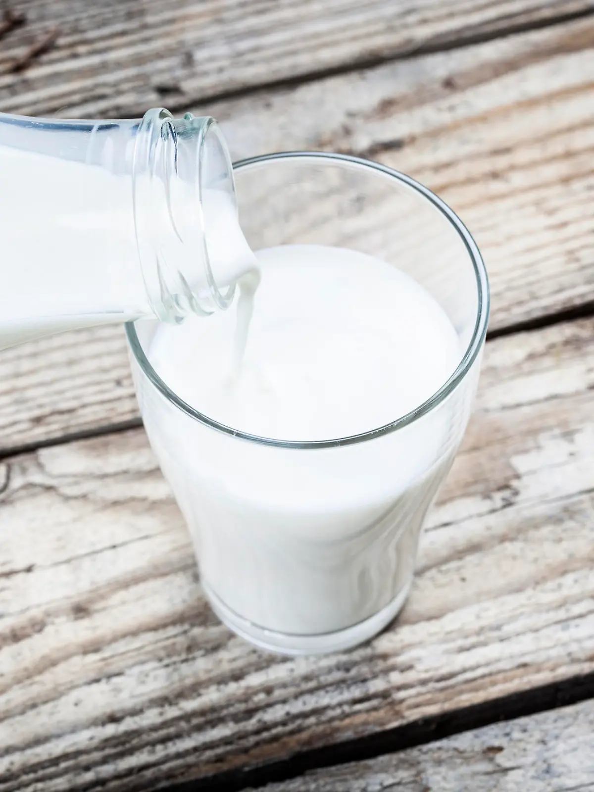 Milch wird in Glas eingeschenkt.