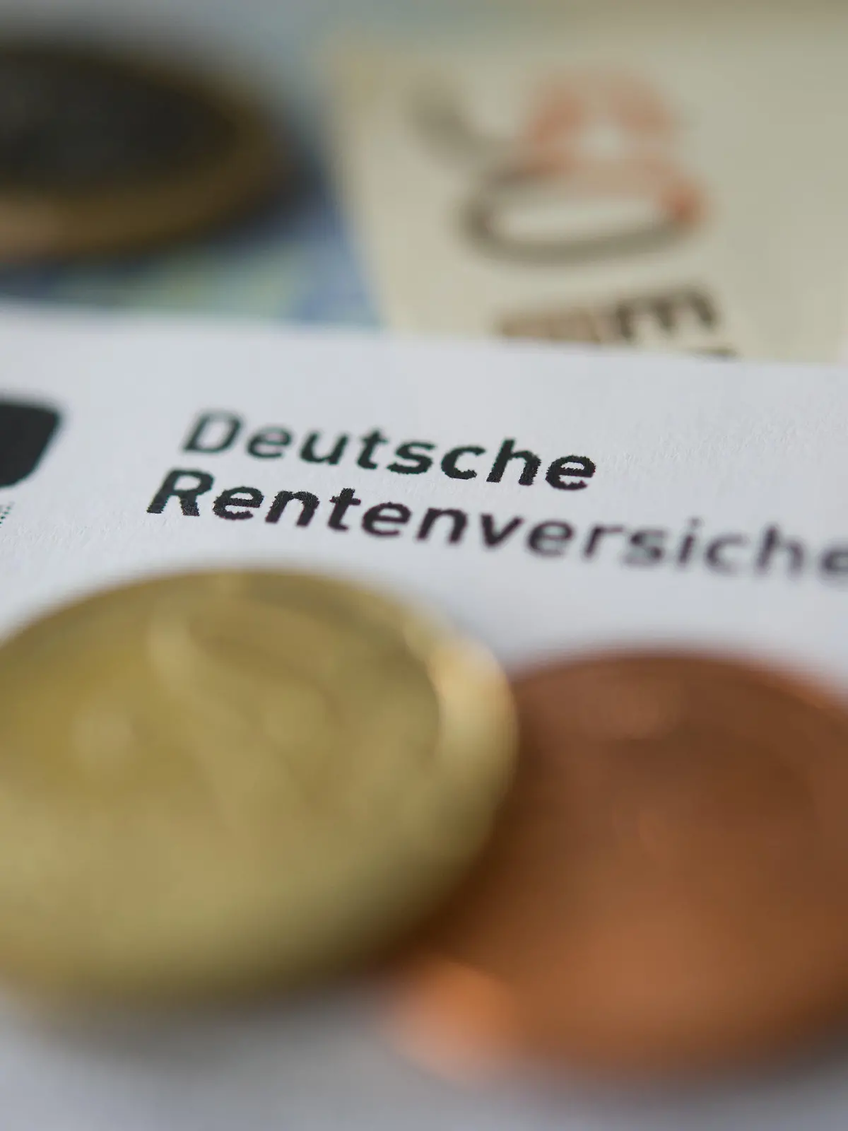 ARCHIV - 21.06.2012, Baden-Württemberg, Stuttgart: ILLUSTRATION - Münzen und Geldscheine liegen neben einem Schreiben mit der Aufschrift «Deutsche Rentenversicherung». (zu dpa «Erwerbstätige ziehen höhere Rentenbeiträge einer späteren Rente vor») Foto: Marijan Murat/dpa +++ dpa-Bildfunk +++