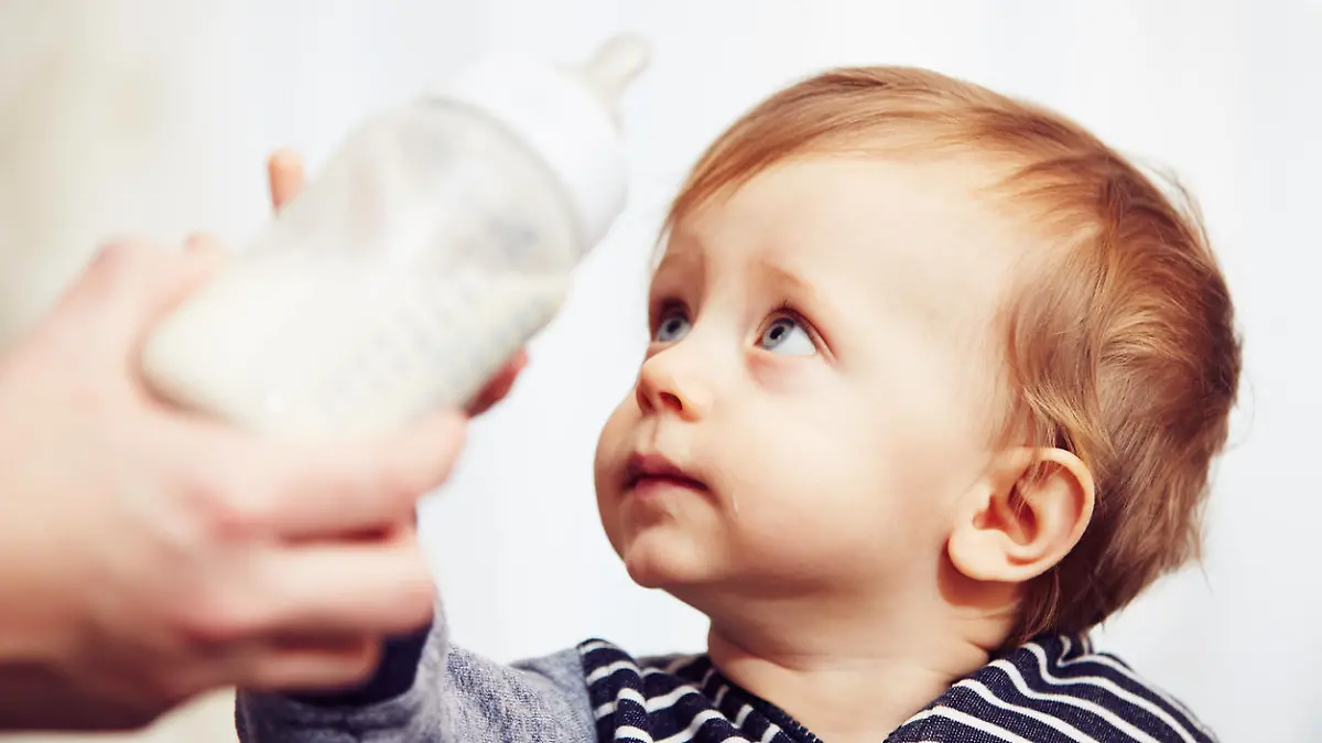 Kleinkind bekommt Flasche mit Milch