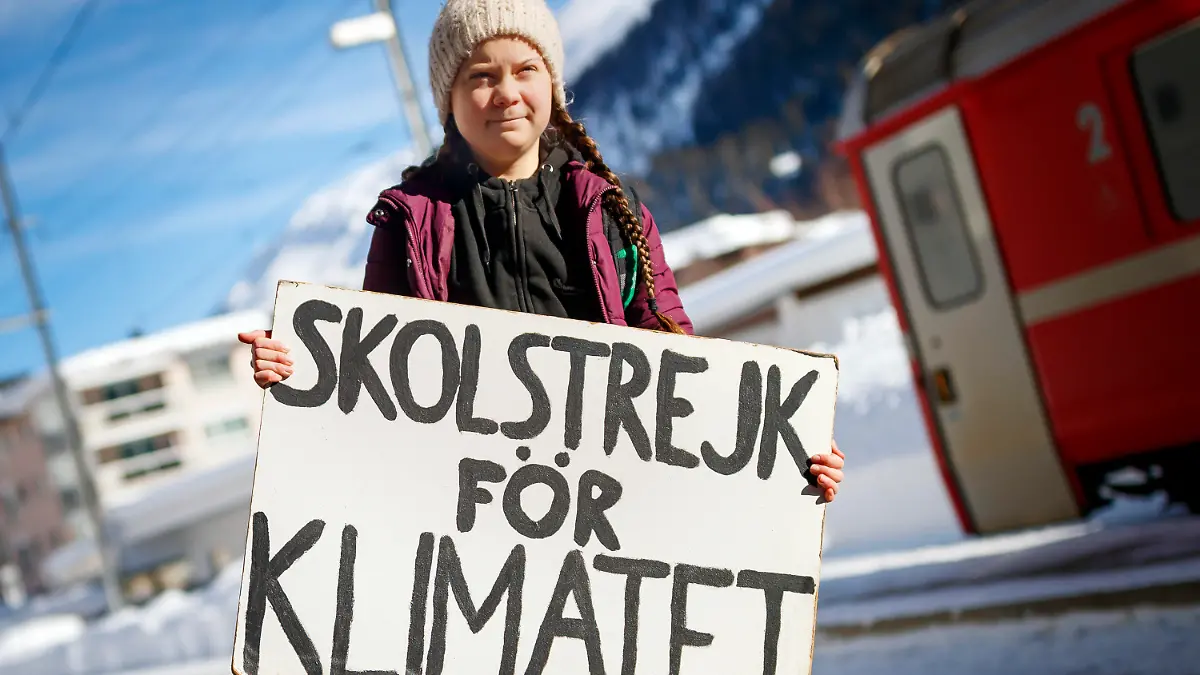 23.01.2019, Schweiz, Davos: Die schwedische Klimaaktivistin Greta Thunberg kommt zur 49. Jahrestagung des Weltwirtschaftsforums an. Thunberg wird von Mittwoch bis Freitag am World Economic Forum in Davos teilnehmen. Weil Flugreisen viel CO2 ausstoßen und damit klimaschädlich sind, hat die schwedische Klimaaktivistin den langen Weg mit der Bahn zurückgelegt. Auf dem Schild steht "Schulstreik für das Klima". Foto: Valentin Flauraud/KEYSTONE/dpa +++ dpa-Bildfunk +++