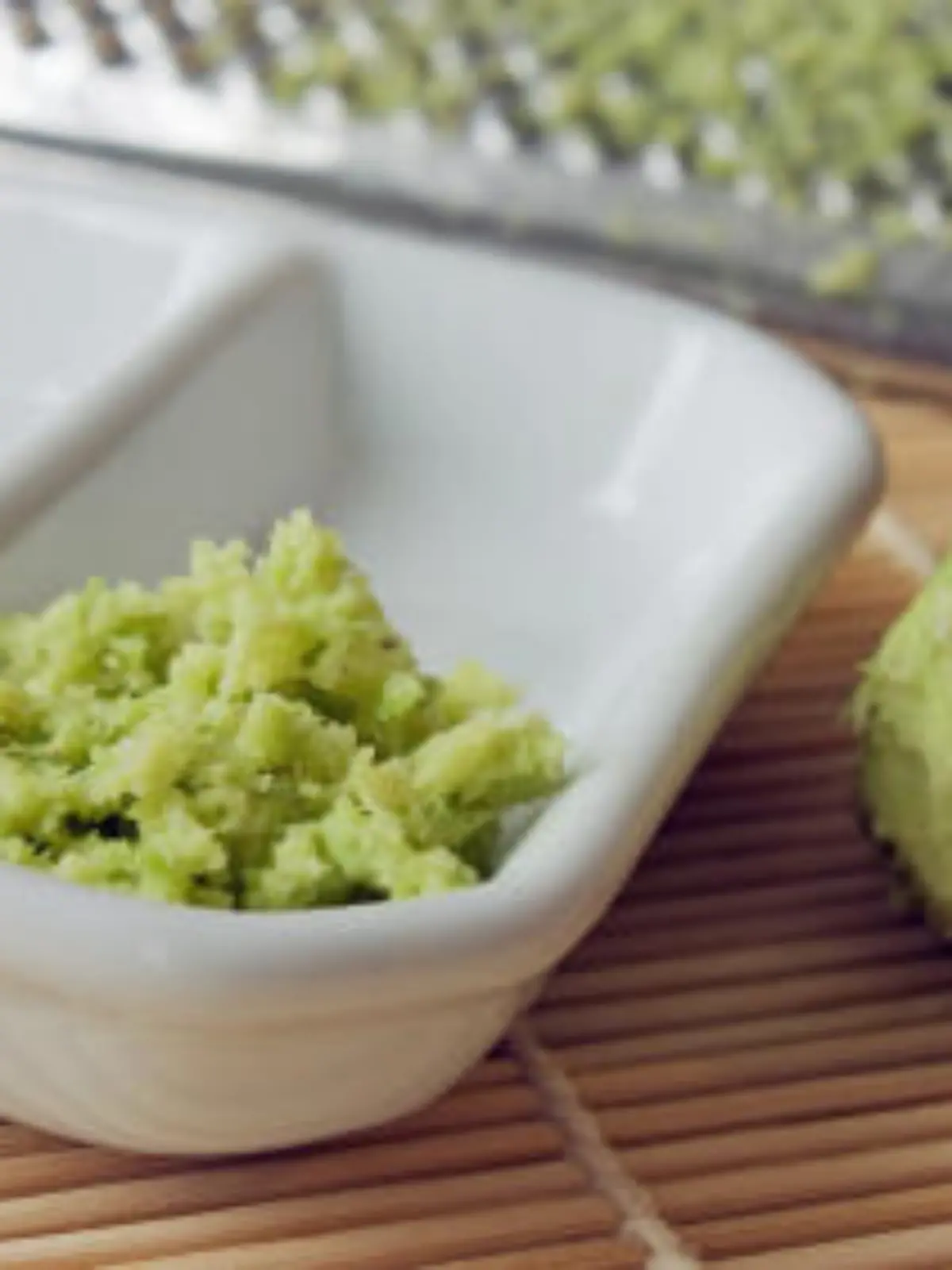 Selective focus imaga of grated fresh wasabi root also called Japanese horseradish on a bamboo mat with soy sauce.