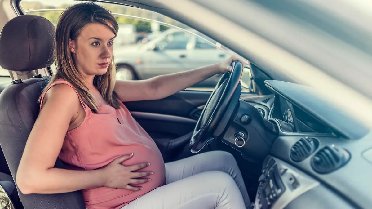 Junge schwangere Frau sitzt in Auto