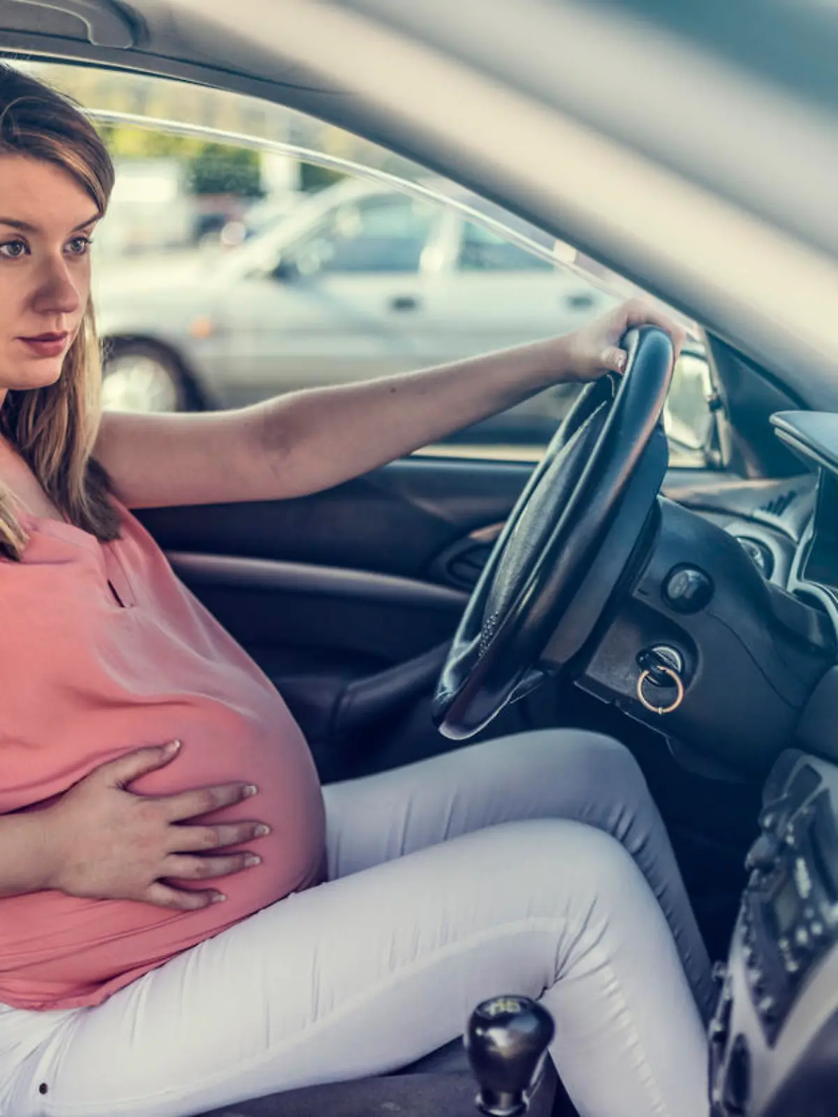 Junge schwangere Frau sitzt in Auto