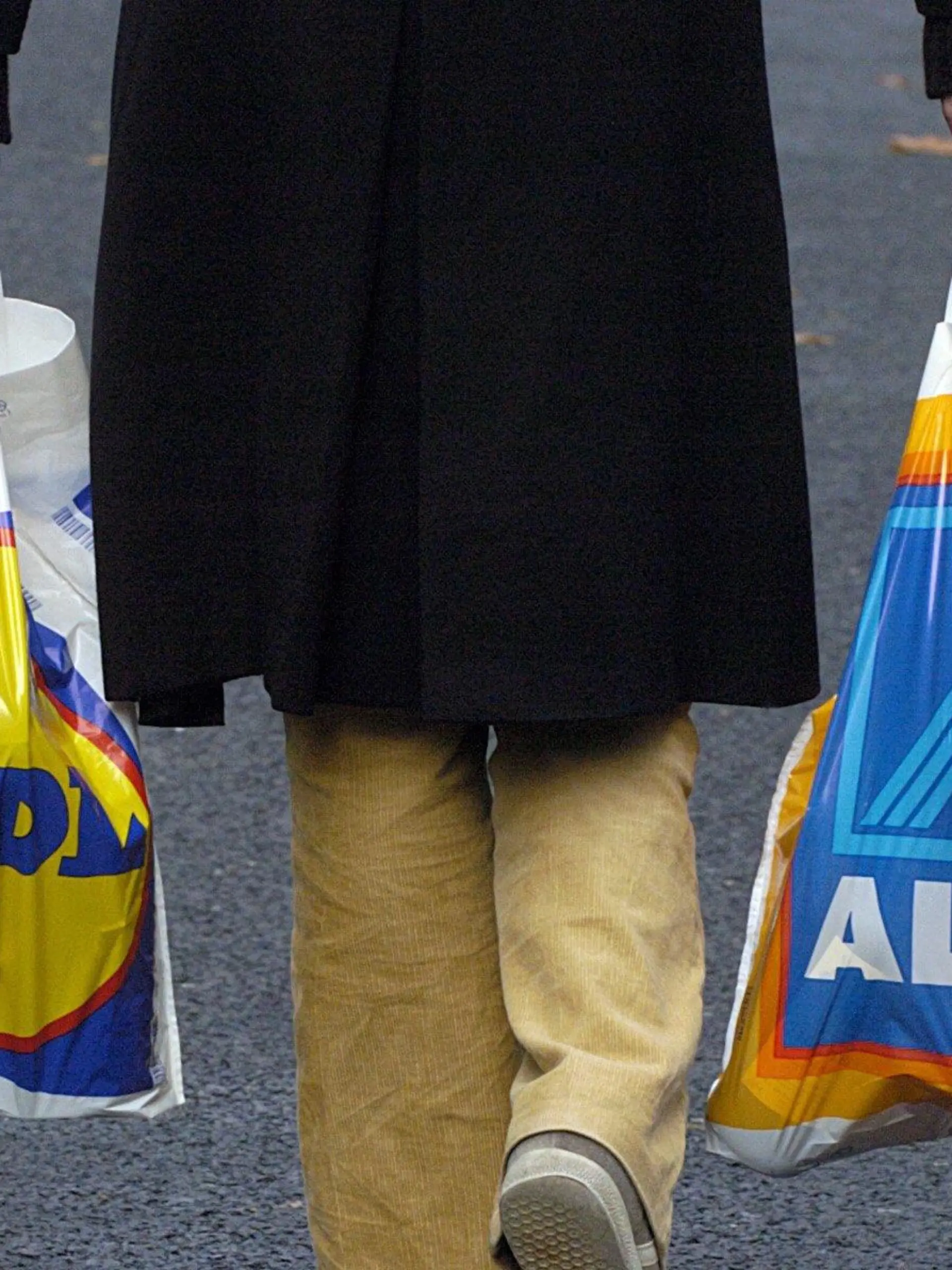 ARCHIV - Eine Frau trägt in Köln jeweils eine Plastiktüte der Lebensmittel-Discounter Lidl und Aldi (Archivfoto vom 17.11.2003). Die Gründer des Lebensmitteldiscounters Aldi, Karl und Theo Albrecht, sind auch in diesem Jahr die mit Abstand reichsten Deutschen. Die Brüder verfügen nach Recherchen des «manager magazins» über ein geschätztes Vermögen von jeweils mehr als 16 Milliarden Euro. Auf dem dritten Platz der am Dienstag (10.10.2006) veröffentlichten Rangliste steht mit Dieter Schwarz ebenfalls ein Handels- und Discountfachmann. Zu seiner Firmengruppe gehören der Discounter Lidl und die Handelskette Kaufland. Das Vermögen von Schwarz wird auf mehr als 10 Milliarden Euro geschätzt. Foto: Oliver Berg dpa/lnw (zu dpa 0348) +++(c) dpa - Bildfunk+++