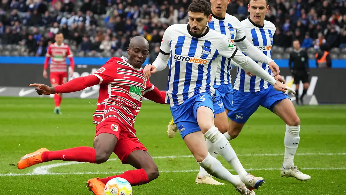 25.02.2023, Berlin: Fußball: Bundesliga, Hertha BSC - FC Augsburg, 22. Spieltag, Olympiastadion, Augsburgs Kelvin Yeboah (l) gegen Herthas Agustin Maximiliano Rogel Paita (M). Foto: Soeren Stache/dpa - WICHTIGER HINWEIS: Gemäß den Vorgaben der DFL Deutsche Fußball Liga bzw. des DFB Deutscher Fußball-Bund ist es untersagt, in dem Stadion und/oder vom Spiel angefertigte Fotoaufnahmen in Form von Sequenzbildern und/oder videoähnlichen Fotostrecken zu verwerten bzw. verwerten zu lassen. +++ dpa-Bildfunk +++
