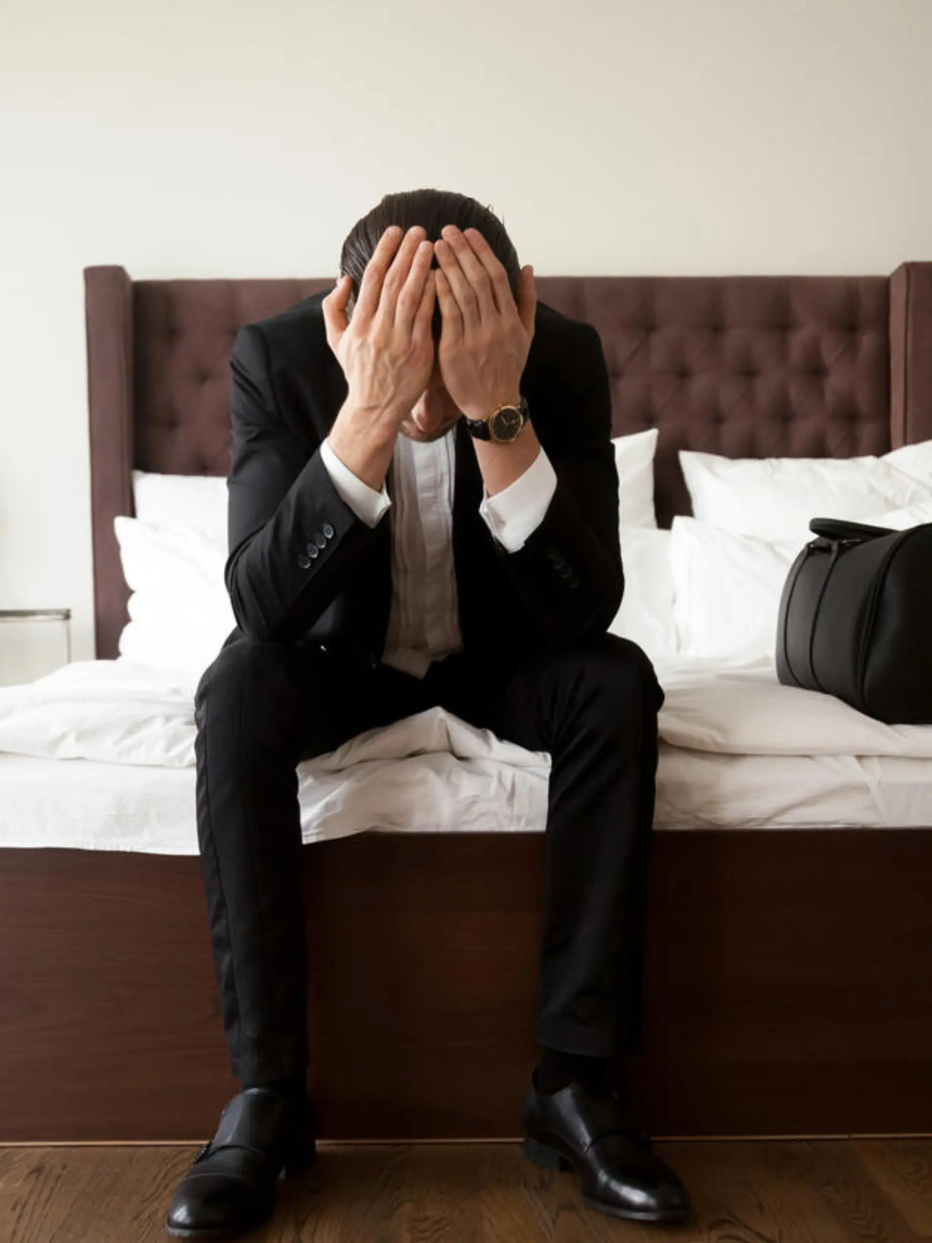 Mann im Anzug sitzt traurig in Hotelzimmer