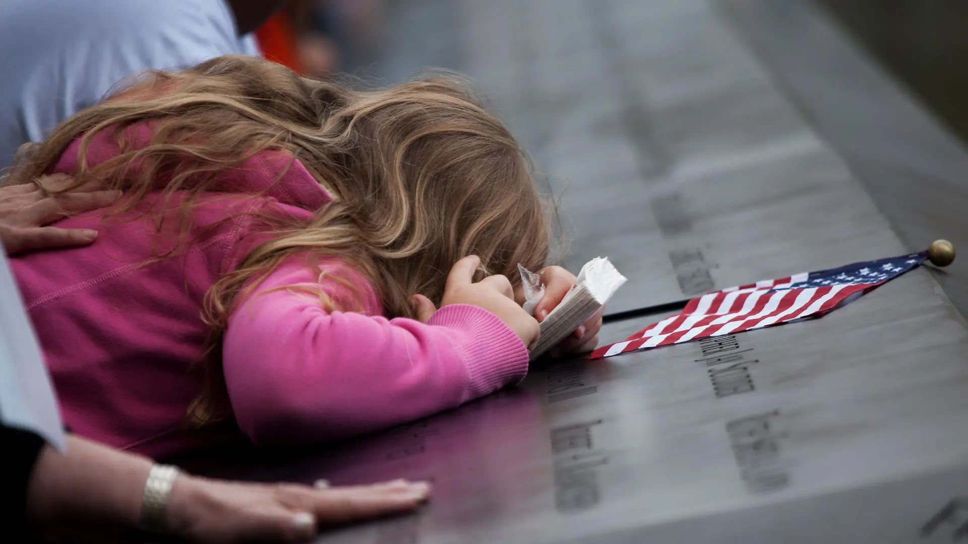 epa02909782 A girl leans over the panels with the victims' names inscribed at the south pool of the 9/11 Memorial during the tenth anniversary ceremonies at the site of the World Trade Center September 11, 2011, in New York, USA. EPA/TODD HEISLER / POOL +++(c) dpa - Bildfunk+++