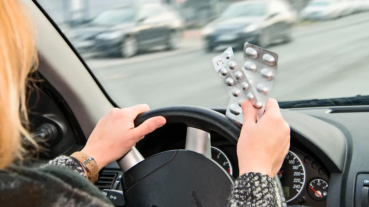 Frau mit Tabletten am Steuer eines Autos
