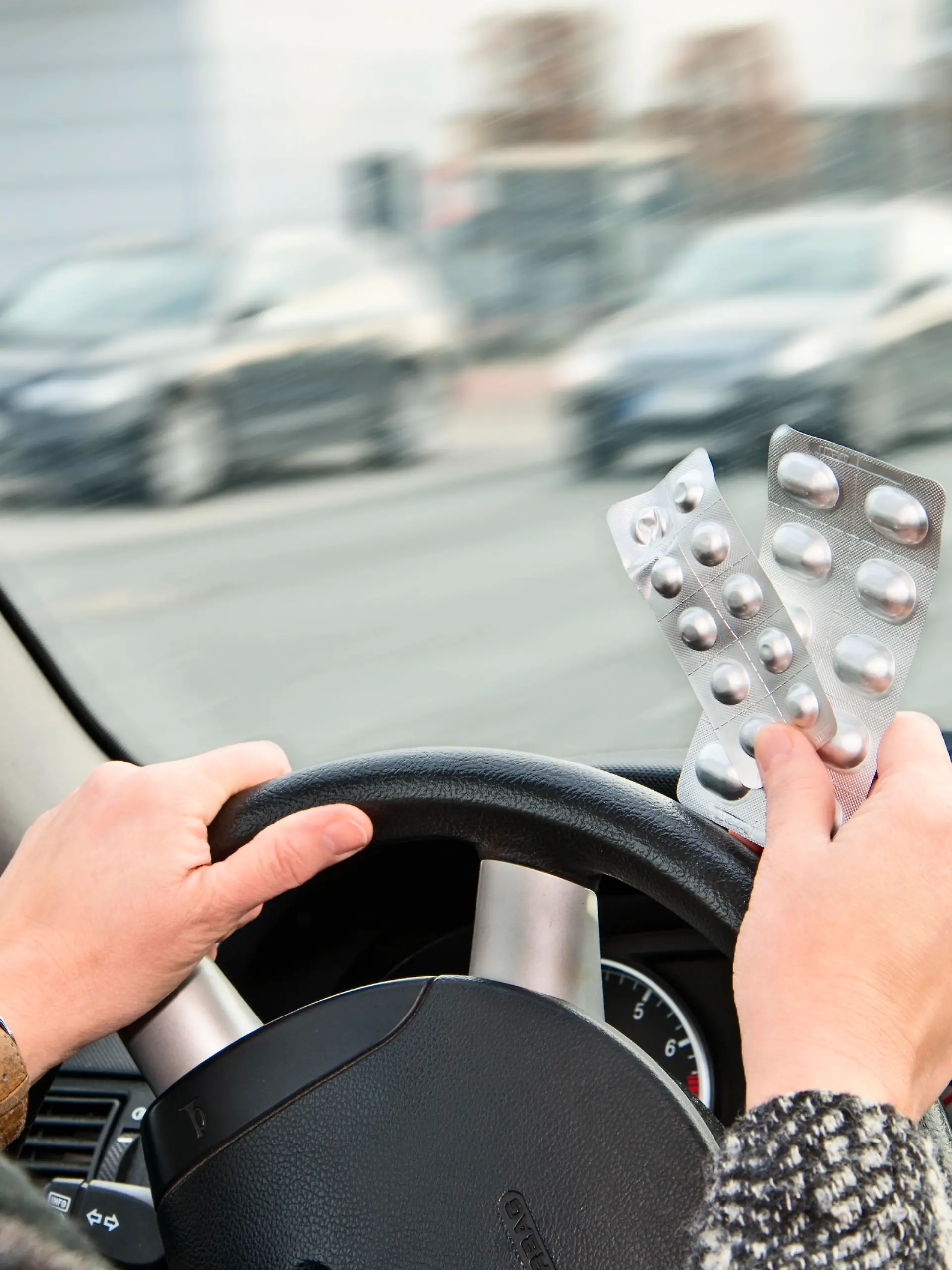Frau mit Tabletten am Steuer eines Autos