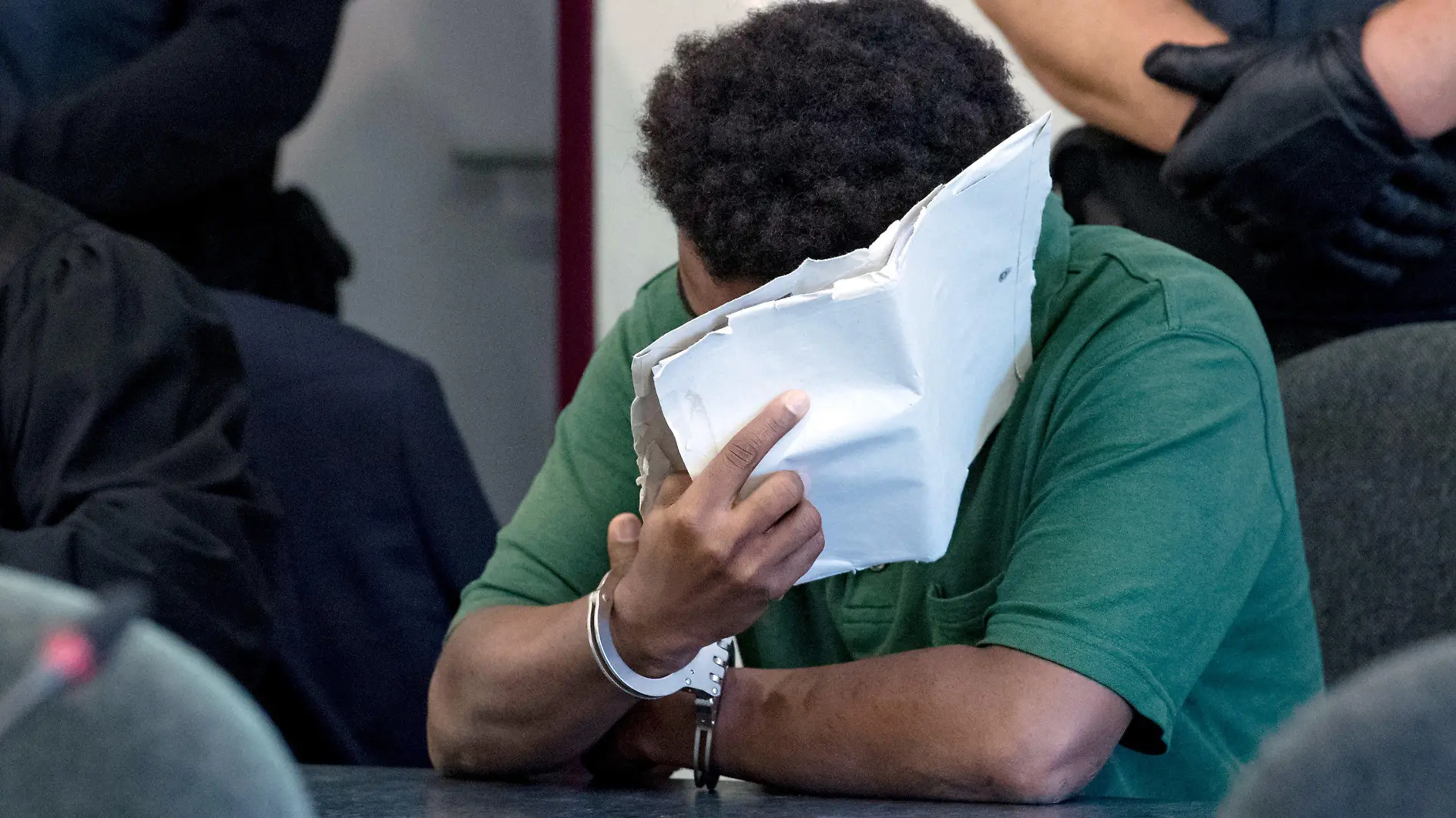 10.09.2019, Sachsen-Anhalt, Dessau-Roßlau: Ein angeklagter 27-jähriger Mann verdeckt im Landgericht Dessau sein Gesicht. Die Staatsanwaltschaft wirft dem derzeit inhaftierten Mann, der aus Niger stammt, schweren sexuellen Missbrauch von Kindern in Tateinheit mit Vergewaltigung und Körperverletzung eines neunjährigen Mädchens vor. Die Tat hat sich im Juni auf den Elbwiesen in Roßlau ereignet. Foto: Hendrik Schmidt/dpa-Zentralbild/dpa +++ dpa-Bildfunk +++