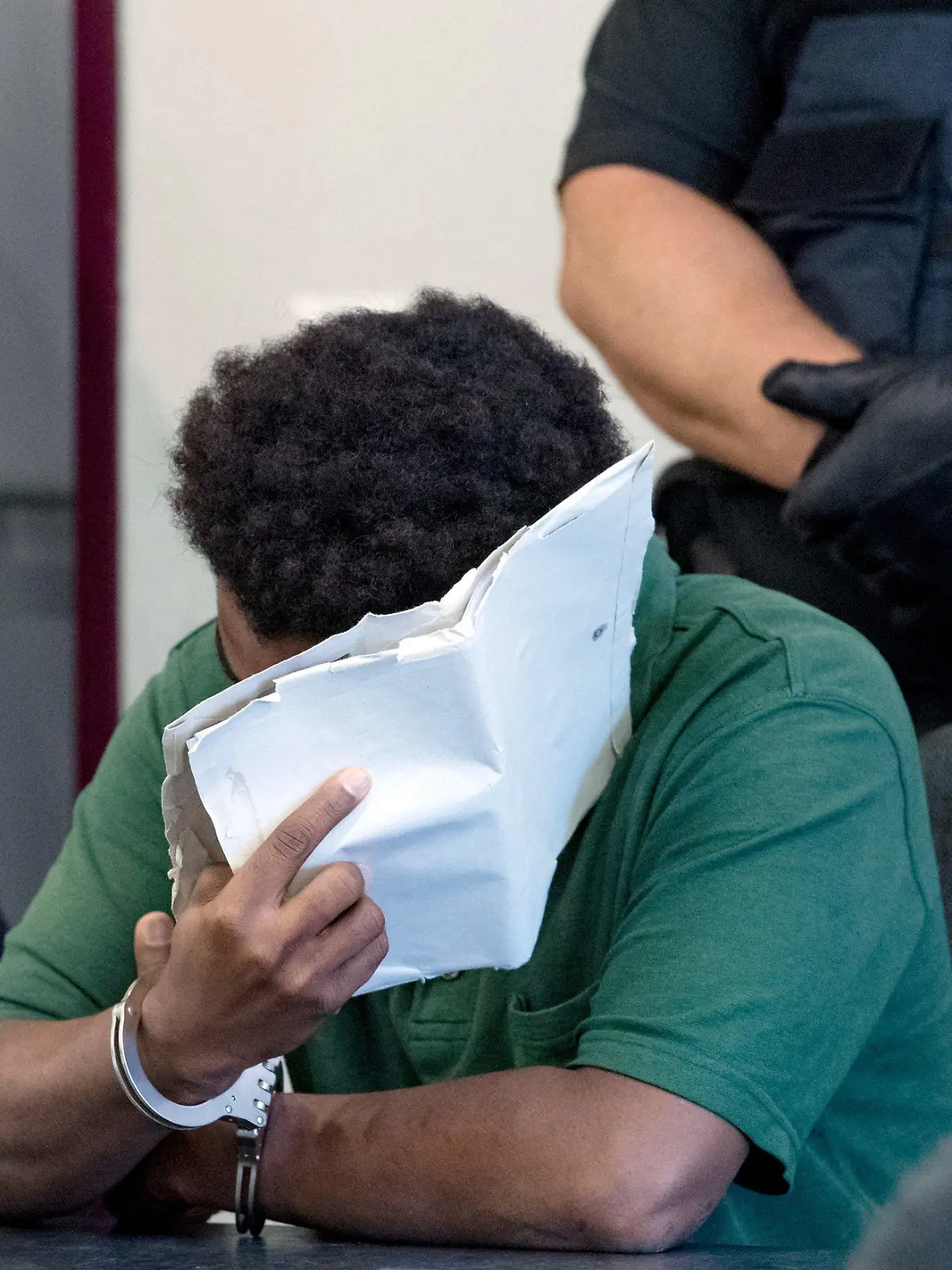 10.09.2019, Sachsen-Anhalt, Dessau-Roßlau: Ein angeklagter 27-jähriger Mann verdeckt im Landgericht Dessau sein Gesicht. Die Staatsanwaltschaft wirft dem derzeit inhaftierten Mann, der aus Niger stammt, schweren sexuellen Missbrauch von Kindern in Tateinheit mit Vergewaltigung und Körperverletzung eines neunjährigen Mädchens vor. Die Tat hat sich im Juni auf den Elbwiesen in Roßlau ereignet. Foto: Hendrik Schmidt/dpa-Zentralbild/dpa +++ dpa-Bildfunk +++