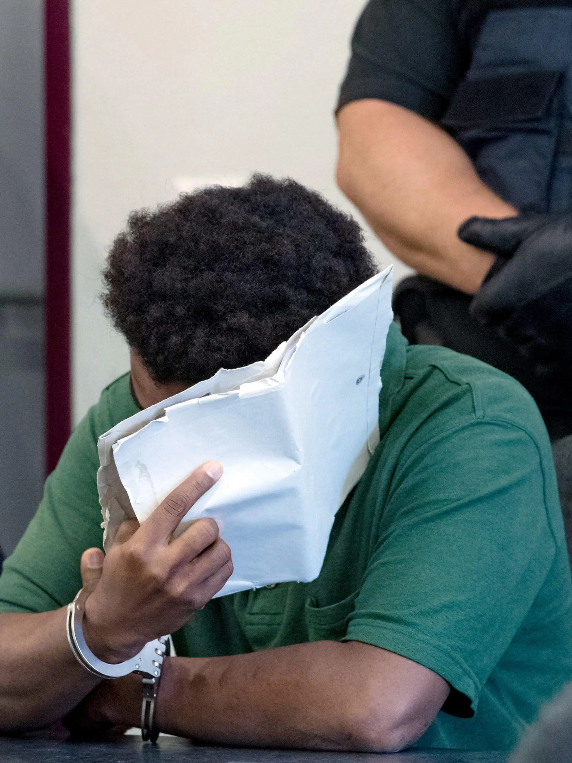 10.09.2019, Sachsen-Anhalt, Dessau-Roßlau: Ein angeklagter 27-jähriger Mann verdeckt im Landgericht Dessau sein Gesicht. Die Staatsanwaltschaft wirft dem derzeit inhaftierten Mann, der aus Niger stammt, schweren sexuellen Missbrauch von Kindern in Tateinheit mit Vergewaltigung und Körperverletzung eines neunjährigen Mädchens vor. Die Tat hat sich im Juni auf den Elbwiesen in Roßlau ereignet. Foto: Hendrik Schmidt/dpa-Zentralbild/dpa +++ dpa-Bildfunk +++