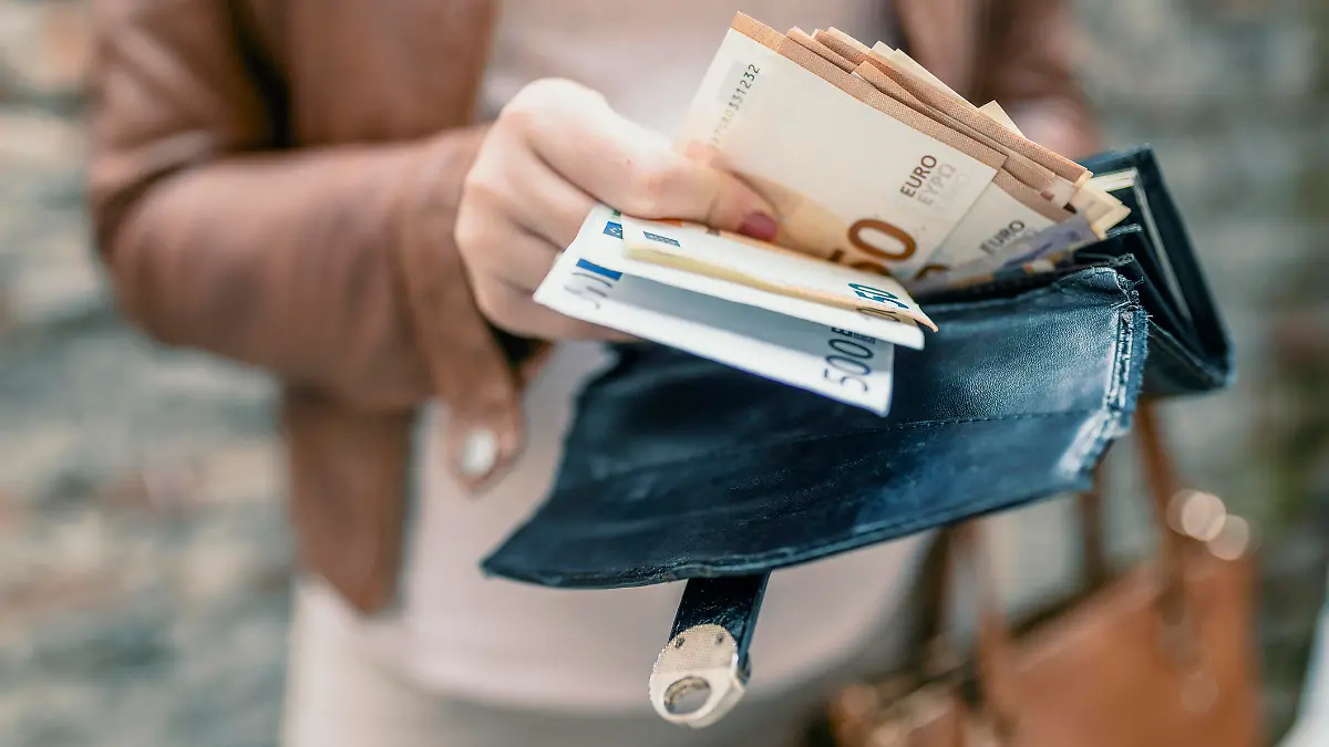 Frau holt Euro-Scheine aus ihrem Portemonnaie