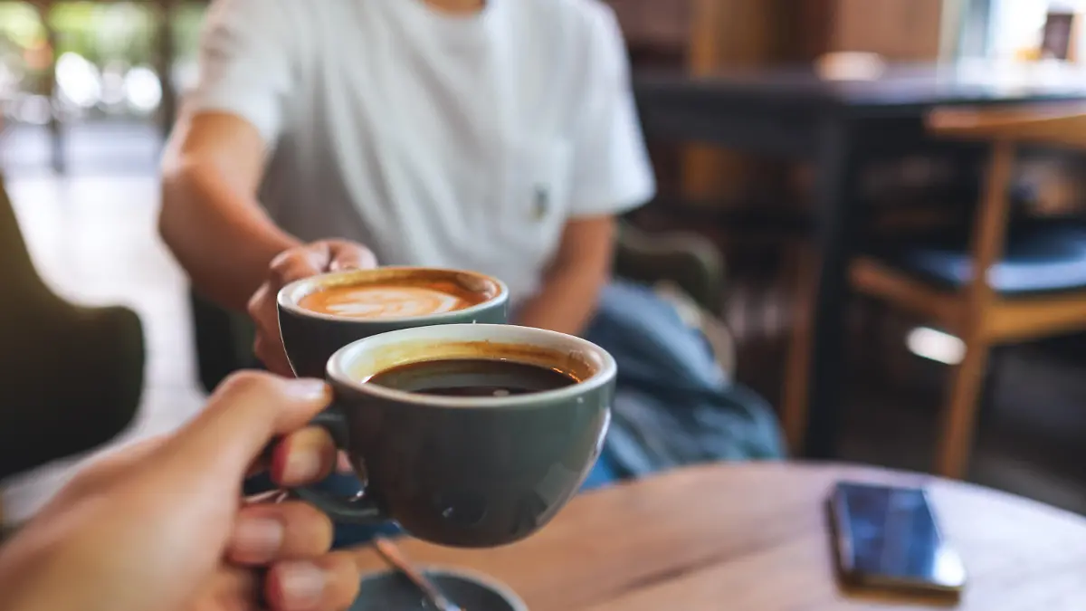 Closeup image of a man and a woman clinking coffee mugs in cafe