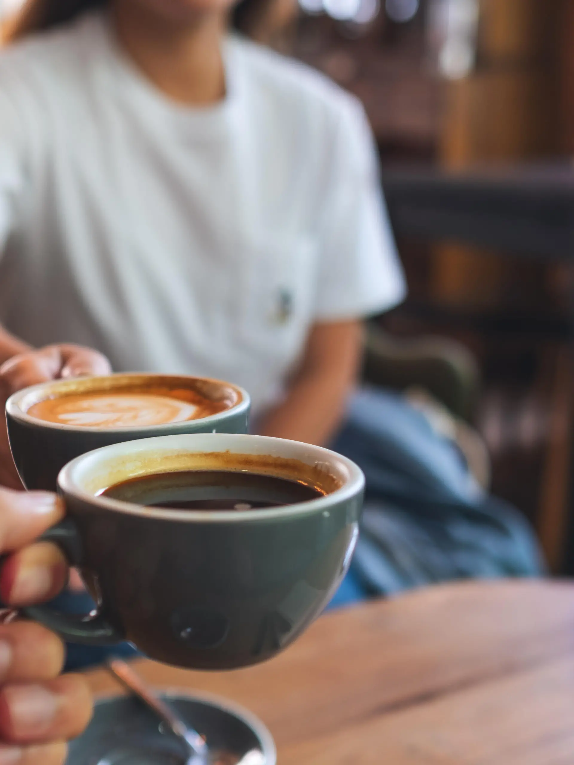 Closeup image of a man and a woman clinking coffee mugs in cafe