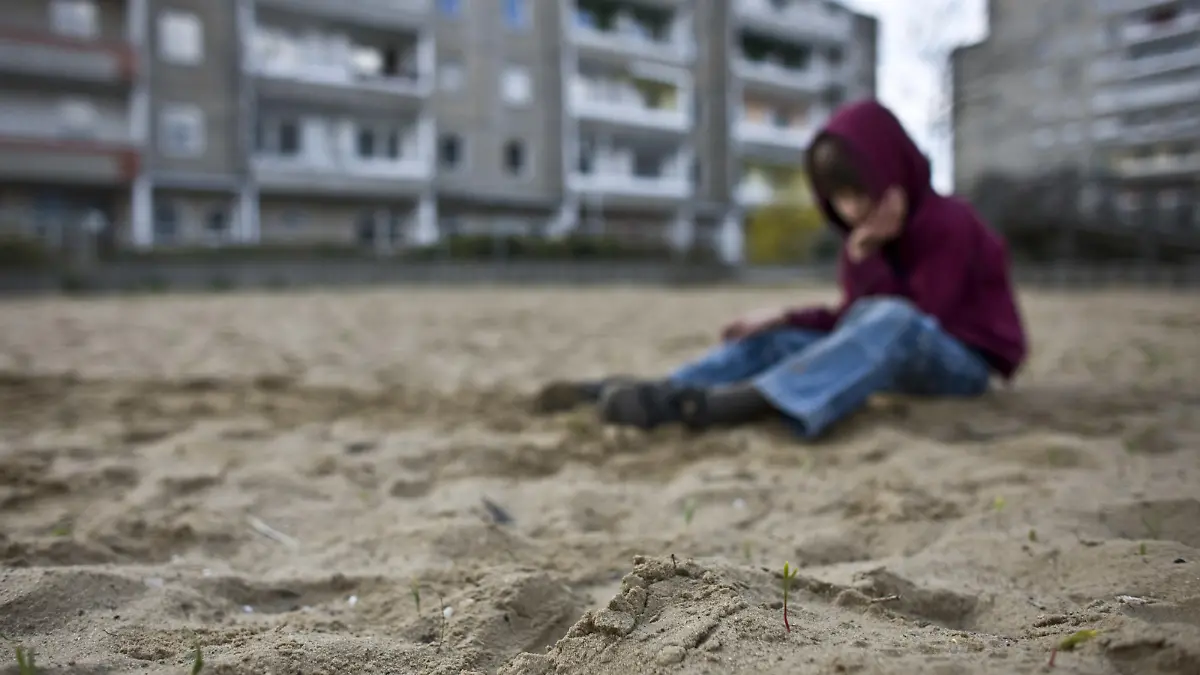 Ein kleiner Junge sitzt traurig und allein im Sand eines Spielplatzes im Innenhof eines Plattenbau-Wohngebiets in Frankfurt (Oder), aufgenommen am 08.04.2008 (gestelltes Symbolbild zum Thema Kinderarmut). Foto: Patrick Pleul +++(c) dpa - Report+++