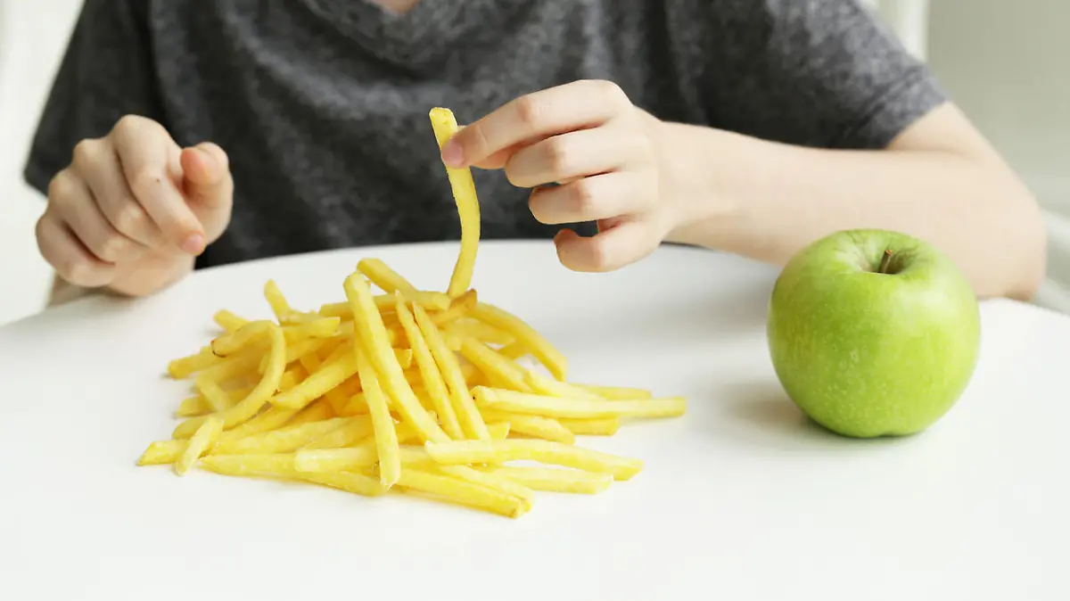 Junge isst Pommes frites statt gesunden Apfel