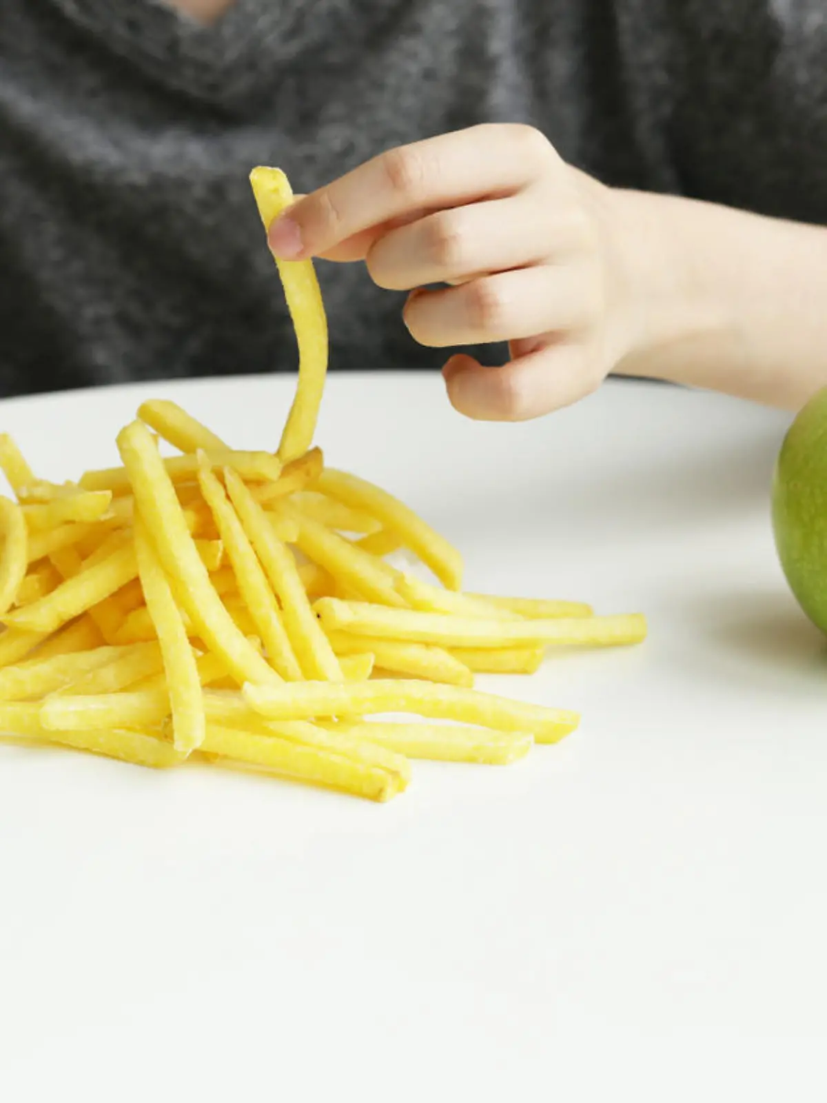 Junge isst Pommes frites statt gesunden Apfel