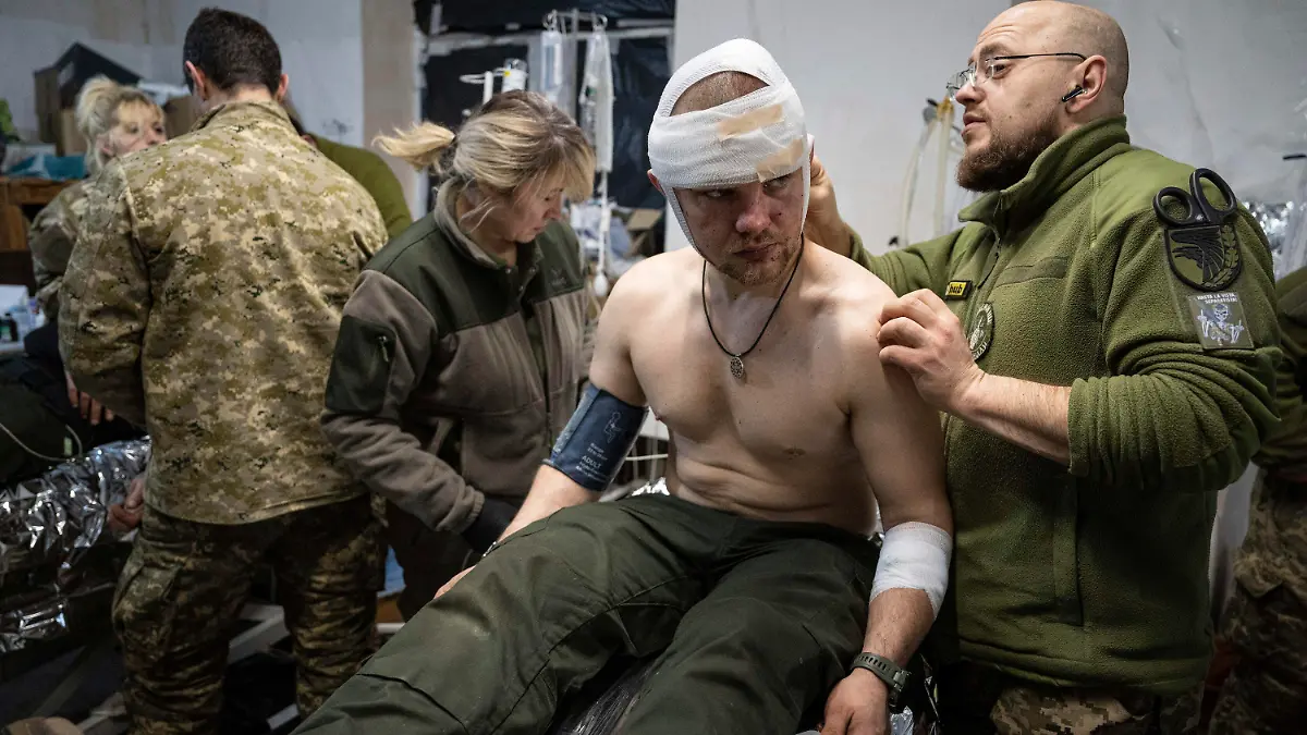 26.02.2023, Ukraine, Bachmut: Ein ukrainischer Militärsanitäter behandelt einen verwundeten Kameraden in einem Feldlazarett in der Nähe von Bachmut. Foto: Evgeniy Maloletka/AP/dpa +++ dpa-Bildfunk +++