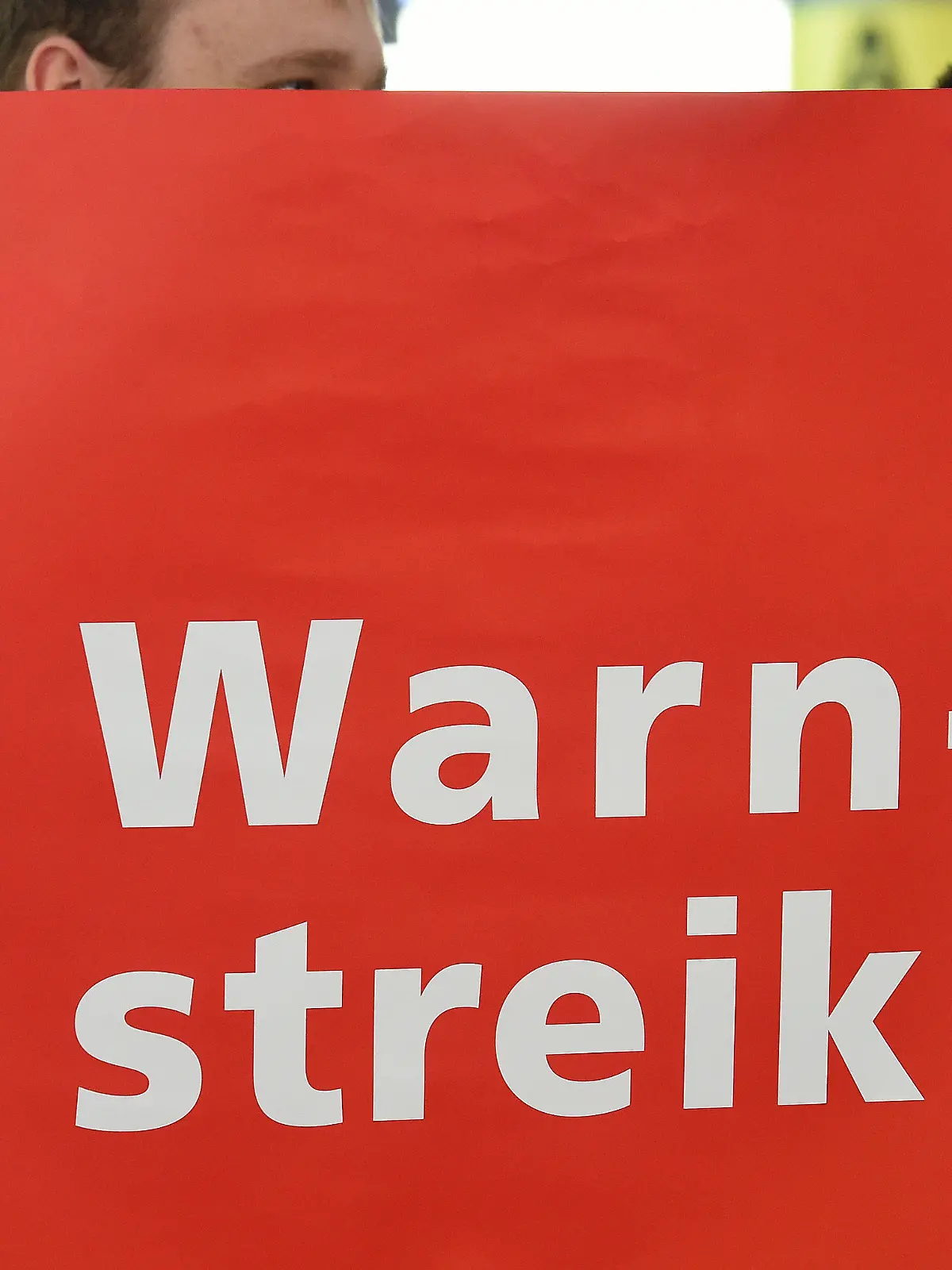ARCHIV - Mit einem Plakat steht ein Mitarbeiter der Fluggast-, Personal- und Warenkontrolle am 30.01.2015 in einer Abflughalle des Flughafens Hannover (Niedersachsen). Foto: Holger Hollemann/dpa  (zu dpa: "Gewerkschaften stimmen auf Warnstreiks im öffentlichen Dienst ein" vom 26.02.2015) +++(c) dpa - Bildfunk+++