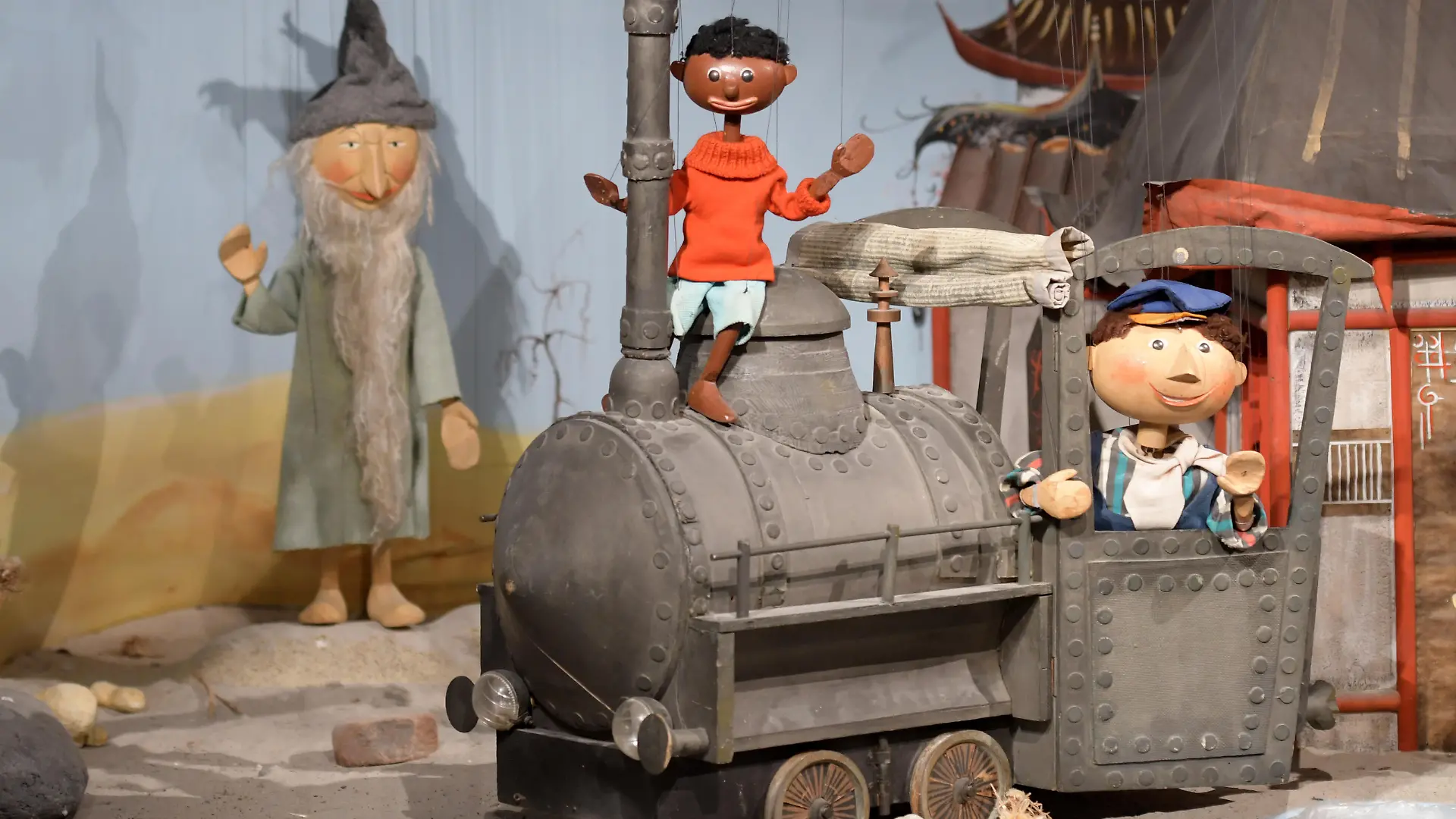 21.02.2018, Bayern, Augsburg: Die Marionetten "Tur Tur" (l-r), "Jim Knopf" und "Lukas" stehen zusammen mit der Lokomotive "Emma" im Puppentheatermuseum. Die Puppenkiste ist eines der bekanntesten Marionettentheater in Deutschland und feiert ihren 70. Geburtstag. Foto: Stefan Puchner/dpa ++