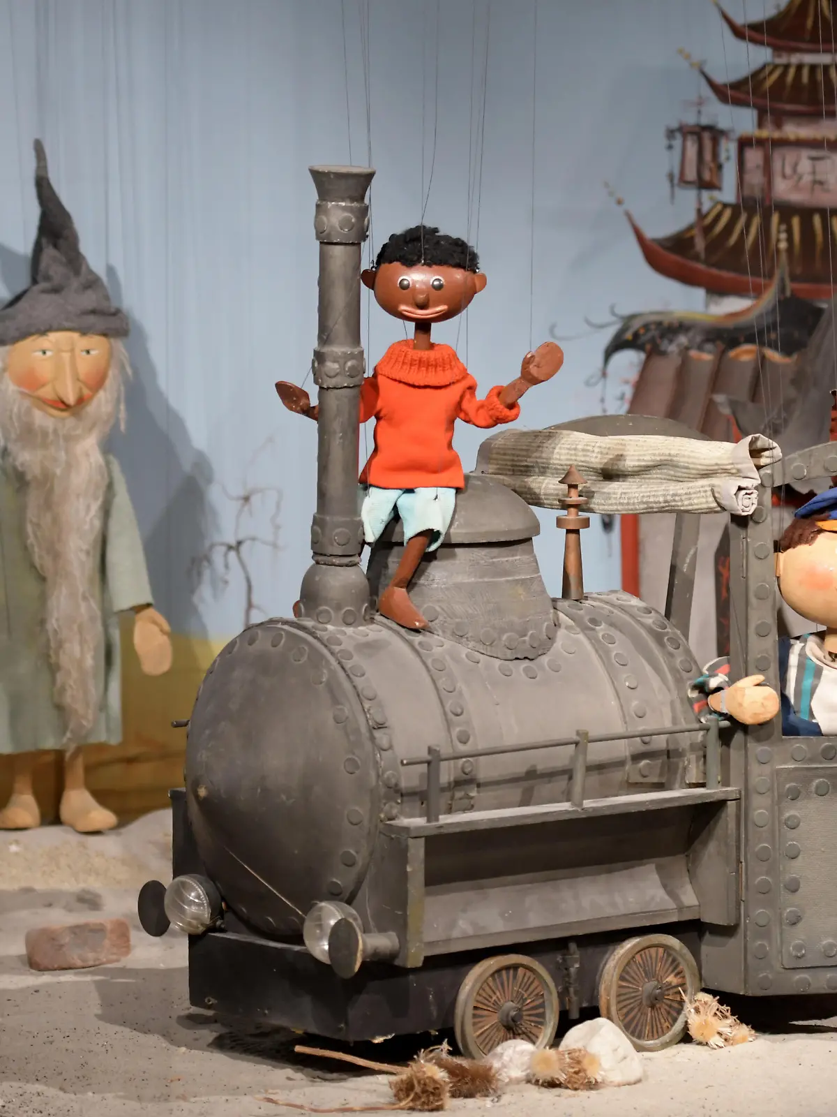 21.02.2018, Bayern, Augsburg: Die Marionetten "Tur Tur" (l-r), "Jim Knopf" und "Lukas" stehen zusammen mit der Lokomotive "Emma" im Puppentheatermuseum. Die Puppenkiste ist eines der bekanntesten Marionettentheater in Deutschland und feiert ihren 70. Geburtstag. Foto: Stefan Puchner/dpa ++