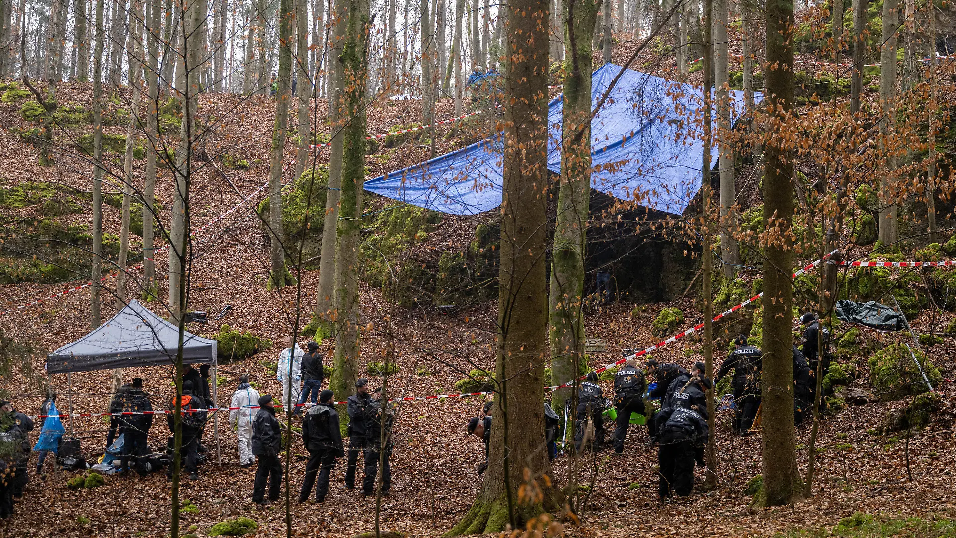 ARCHIV - 30.03.2022, Bayern, Größdorf: Polizisten suchen ein Gebiet im Wald ab, an dem zuvor menschliche Knochen in einer Felsspalte gefunden worden sind. Die Ermittlungen ergaben einen Zusammenhang mit dem Fall der seit 1995 vermissten und wohl ermordeten Münchnerin Sonja Engelbrecht. (zu dpa «Ermittler: Mörder von Sonja Engelbrecht war fit und kannte sich aus») Foto: Peter Kneffel/dpa +++ dpa-Bildfunk +++