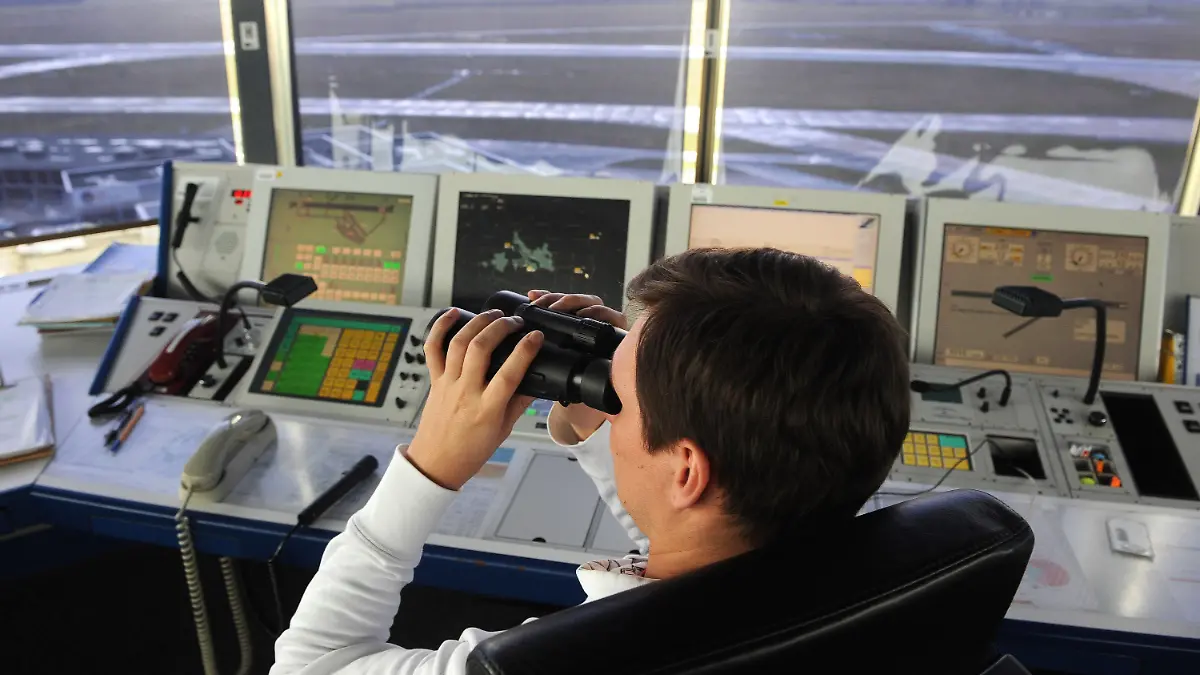 Ein Fluglotse auf dem Tower am Flughafen in Bremen schaut am 07.01.2014 mit dem Fernglas über das Vorfeld des Airports. Am Abend des 6. Januar störte für längere Zeit ein unbekanntes Flugobjekt über dem Airportgelände den Flugbetrieb in der Hansestadt. Die Polizei ermittelt wegen Gefährdung des Flugverkehrs. Foto: Ingo Wagner/dpa +++(c) dpa - Bildfunk+++