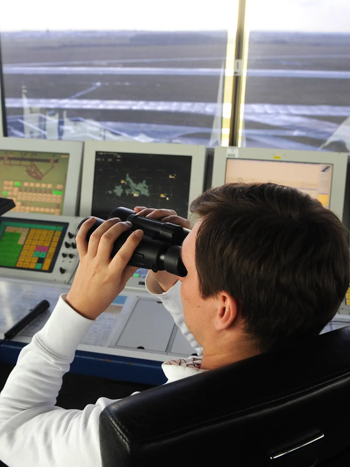 Ein Fluglotse auf dem Tower am Flughafen in Bremen schaut am 07.01.2014 mit dem Fernglas über das Vorfeld des Airports. Am Abend des 6. Januar störte für längere Zeit ein unbekanntes Flugobjekt über dem Airportgelände den Flugbetrieb in der Hansestadt. Die Polizei ermittelt wegen Gefährdung des Flugverkehrs. Foto: Ingo Wagner/dpa +++(c) dpa - Bildfunk+++