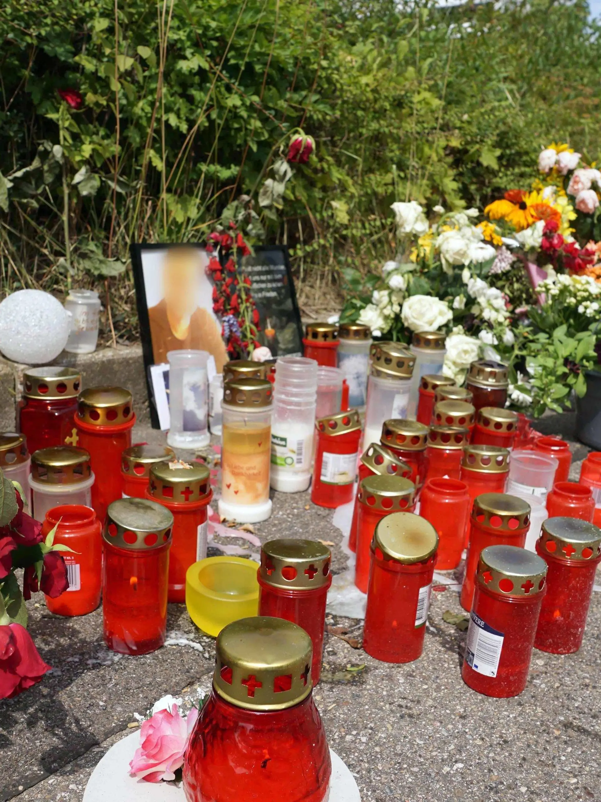 05.08.2019, Baden-Württemberg, Stuttgart: Kerzen und Blumen stehen am Tatort um ein Porträt des dort getöteten Mannes herum. Die Bestürzung ist auch Tage nach dem Schwert-Angriff in Stuttgart weiterhin groß. Der inzwischen in Untersuchungshaft sitzende mutmaßliche Täter hatte nach Angaben der Staatsanwaltschaft ausschließlich persönliche Beweggründe. Foto: Andreas Rosar/dpa - ACHTUNG: Die Person auf dem Porträt wurde aus rechtlichen Gründen gepixelt +++ dpa-Bildfunk +++