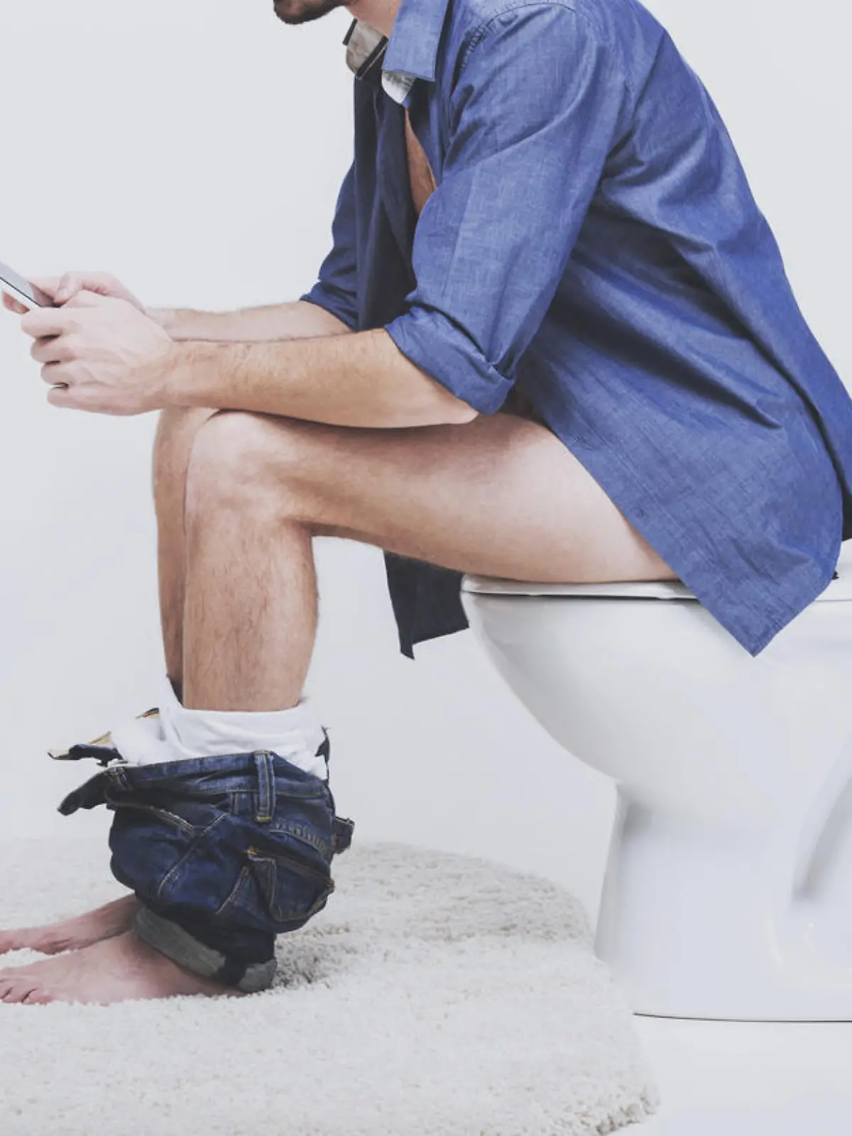 Mann sitzt auf Toilette