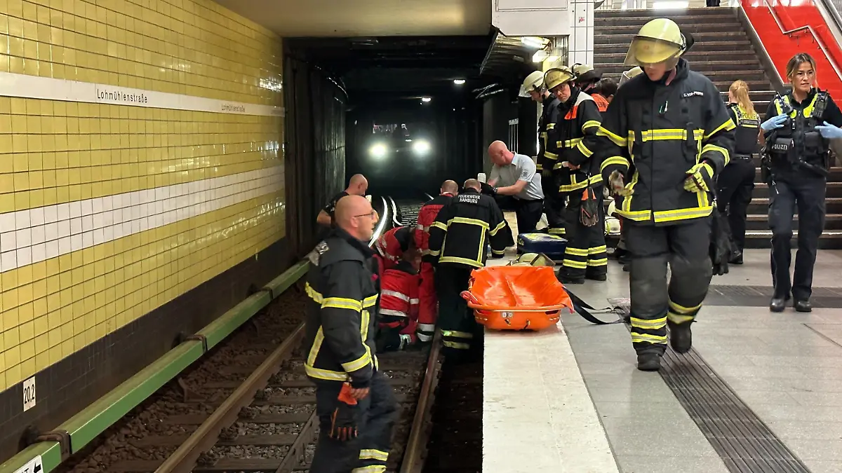 15.08.2023, Hamburg: Feuerwehrleute bei der Rettungsarbeiten am U-Bahnhof Lohmühlenstraße. Dank des schnellen Reagierens der Mitarbeiter der U-Bahnwache in Hamburg konnte einem älteren Herren am Dienstagabend das Leben gerettet werden. Nach seinem Sturz ins Gleisbett schoben ihn die Helfer in einen Hohlrraum unter dem Bahnsteig und stoppten den Zug. Foto: Steven Hutchigs/dpa +++ dpa-Bildfunk +++