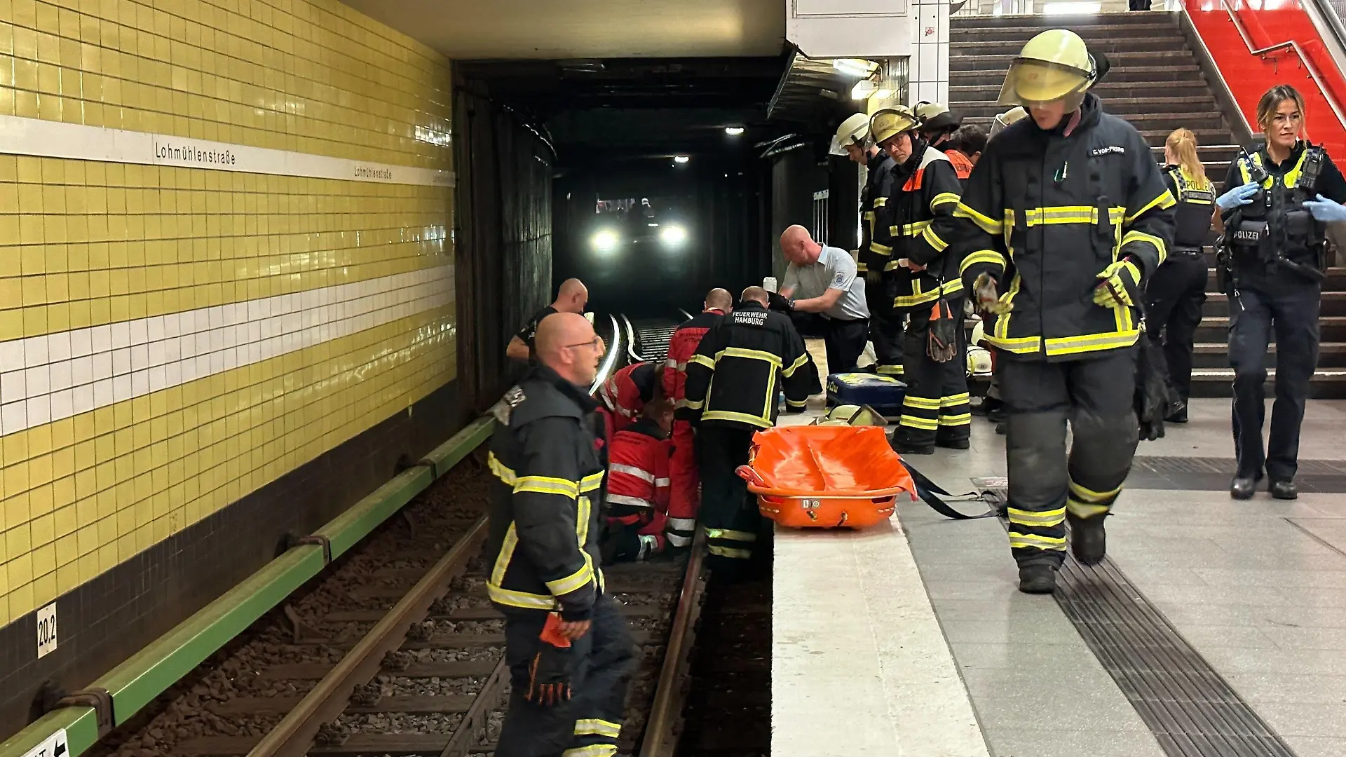 15.08.2023, Hamburg: Feuerwehrleute bei der Rettungsarbeiten am U-Bahnhof Lohmühlenstraße. Dank des schnellen Reagierens der Mitarbeiter der U-Bahnwache in Hamburg konnte einem älteren Herren am Dienstagabend das Leben gerettet werden. Nach seinem Sturz ins Gleisbett schoben ihn die Helfer in einen Hohlrraum unter dem Bahnsteig und stoppten den Zug. Foto: Steven Hutchigs/dpa +++ dpa-Bildfunk +++
