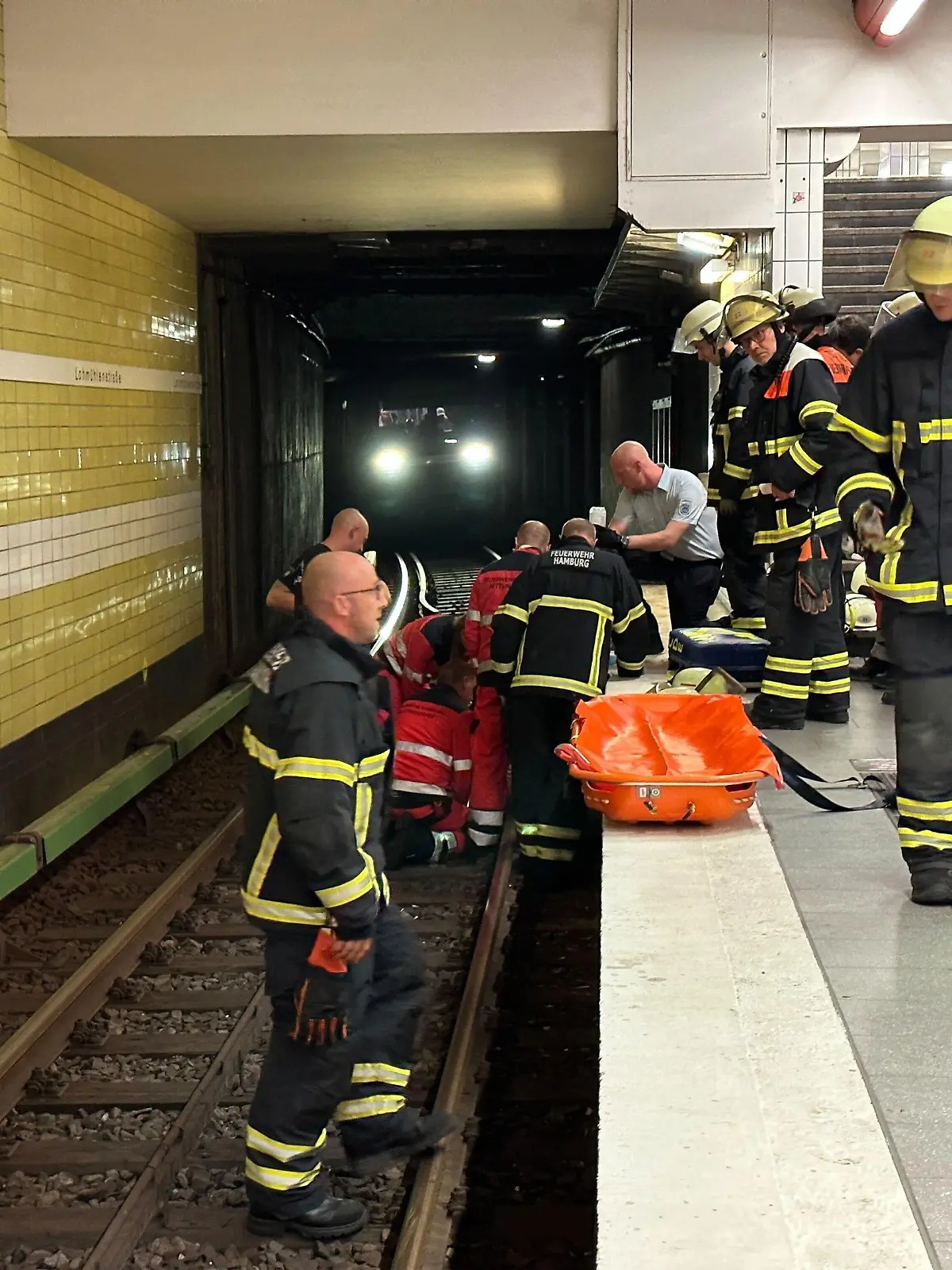 15.08.2023, Hamburg: Feuerwehrleute bei der Rettungsarbeiten am U-Bahnhof Lohmühlenstraße. Dank des schnellen Reagierens der Mitarbeiter der U-Bahnwache in Hamburg konnte einem älteren Herren am Dienstagabend das Leben gerettet werden. Nach seinem Sturz ins Gleisbett schoben ihn die Helfer in einen Hohlrraum unter dem Bahnsteig und stoppten den Zug. Foto: Steven Hutchigs/dpa +++ dpa-Bildfunk +++