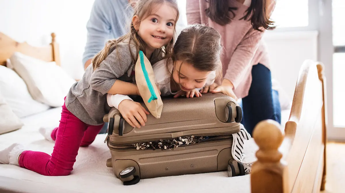 Portrait of a young happy family with two children packing for holiday at home.