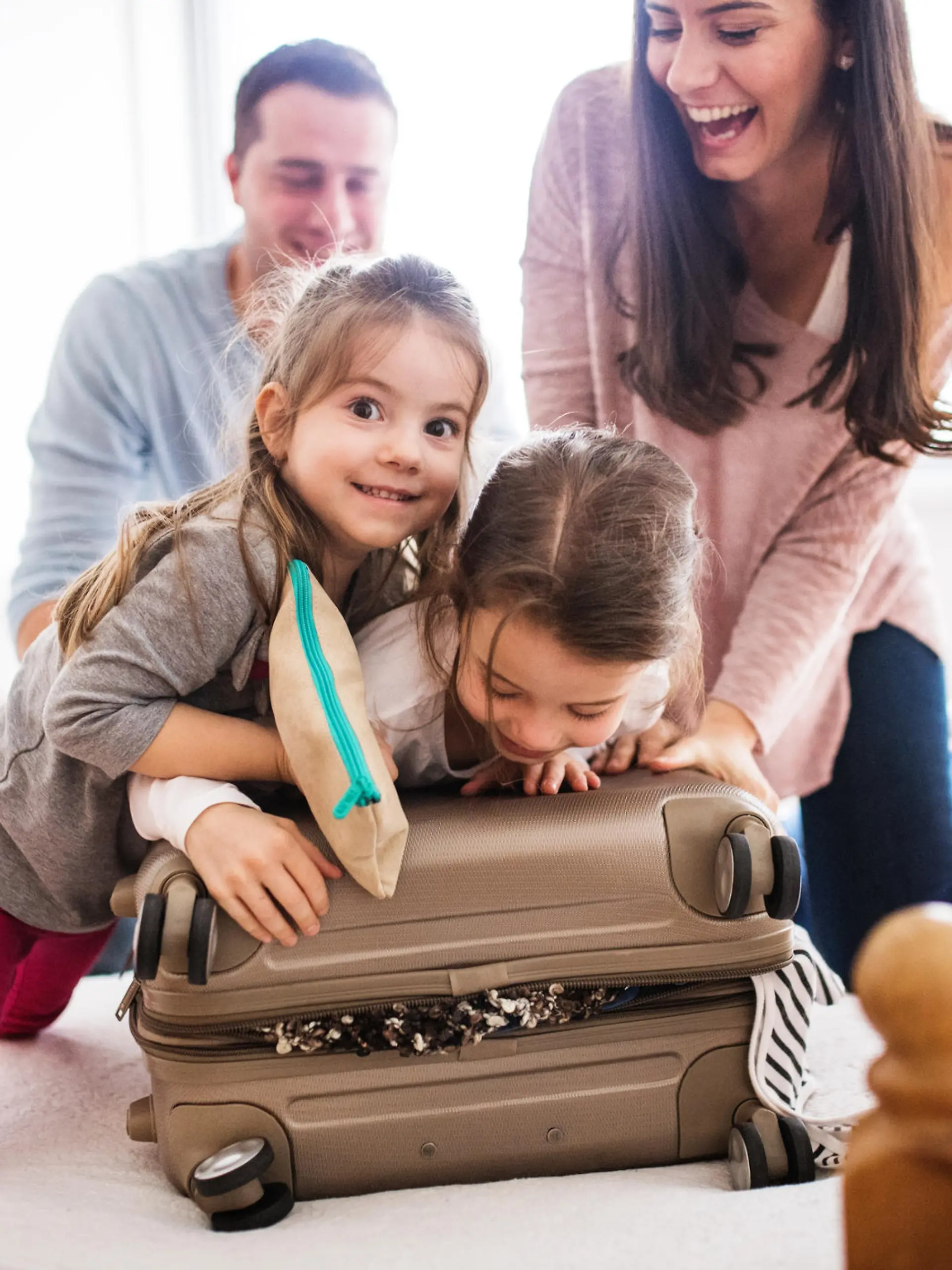 Portrait of a young happy family with two children packing for holiday at home.