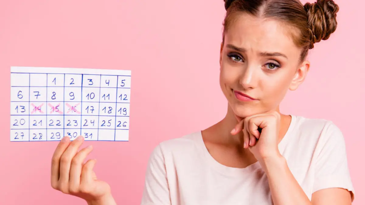 Portrait of puzzled, scared, uncertain youth lady in white t-shirt hold reminder in hands touch chin by hands look at camera isolated on vivid pink background